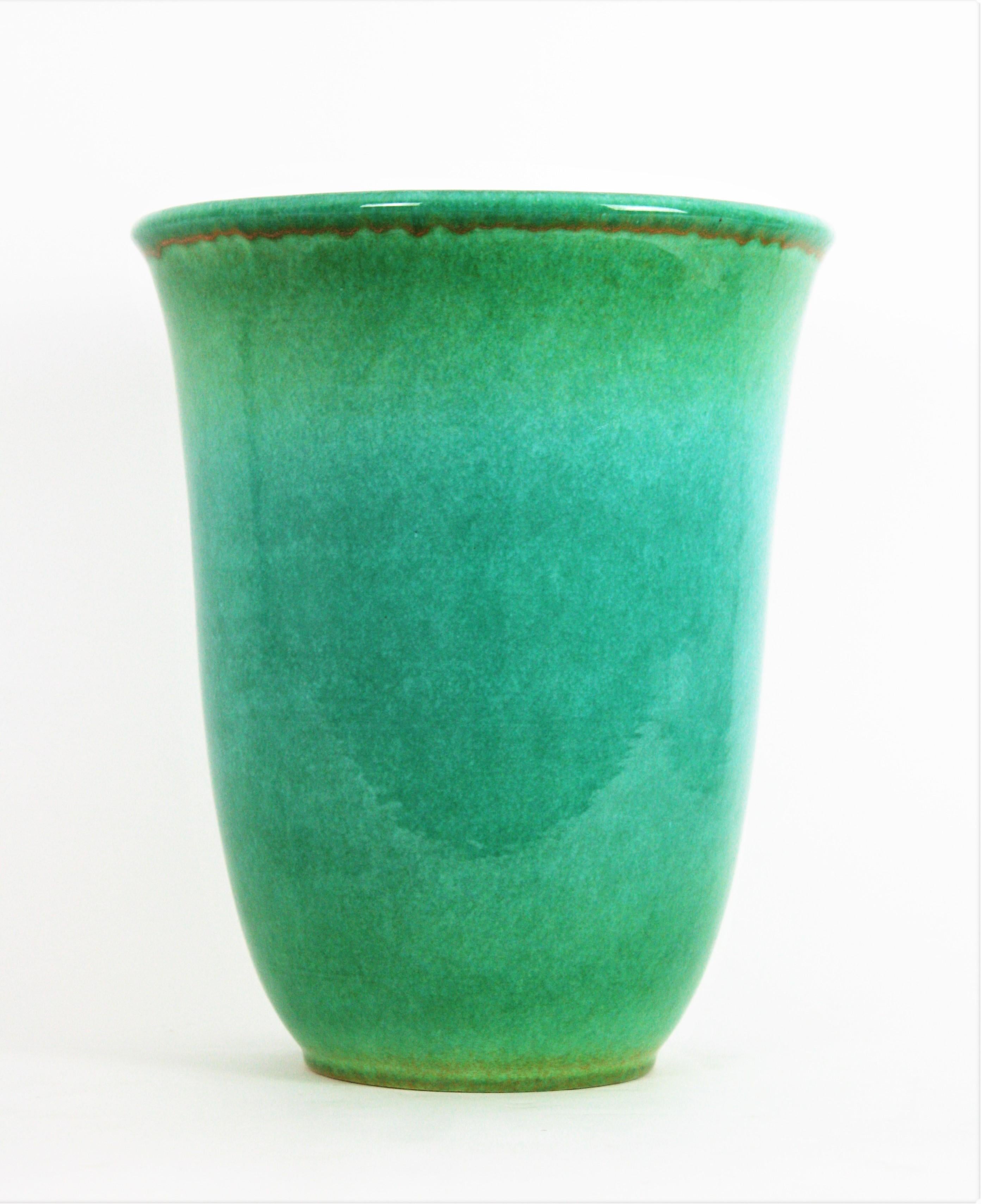 Massive Art Deco Turquoise blue ceramic vase with gilt accents by Serra, Spain, 1930s.
This elegant bell-shaped vase was designed by Josep Serra and manufactured by Cerámicas Serra. It has an amazing color with shades from green to turquoise blue