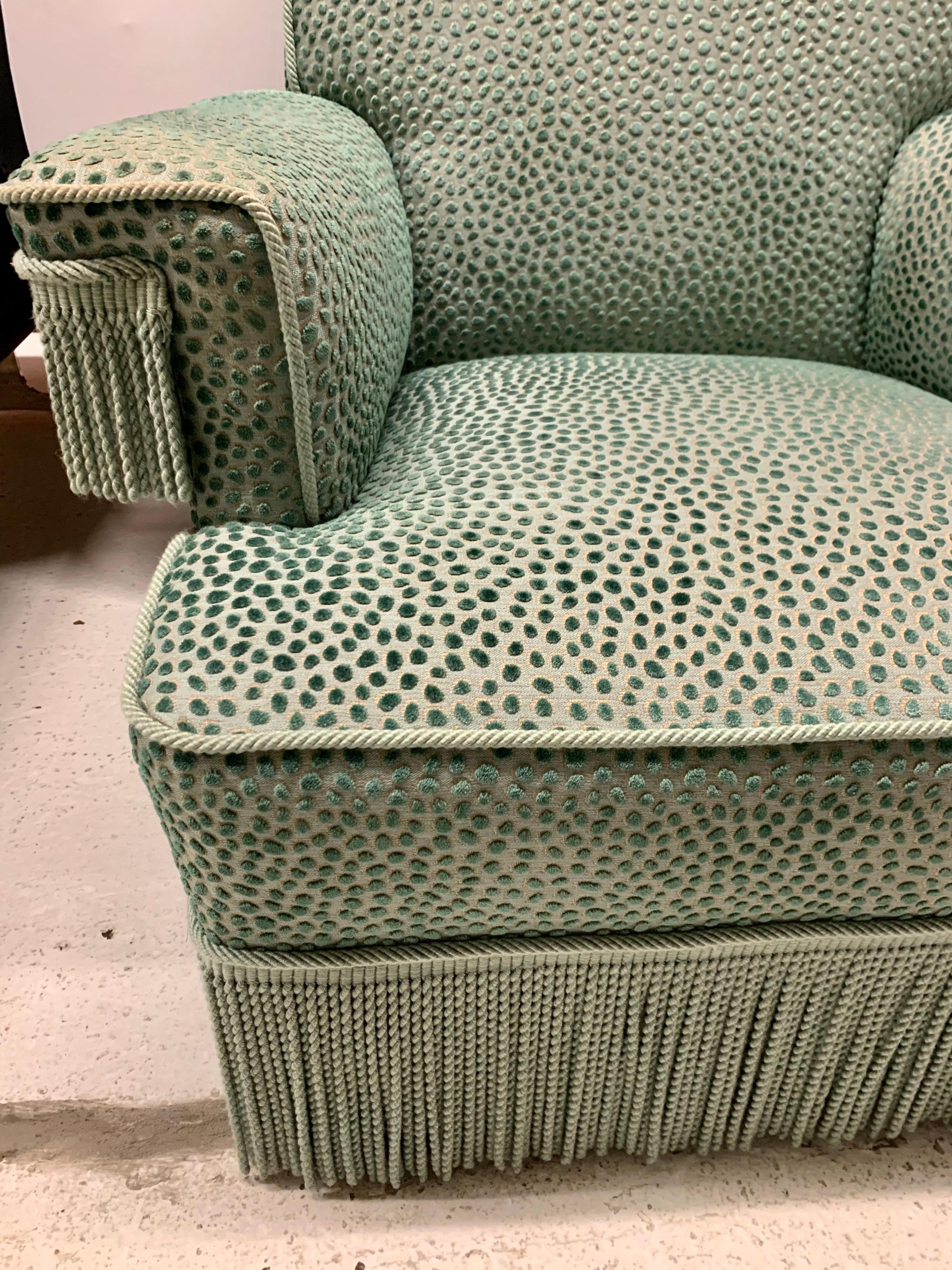Regal pair of armchairs upholstered in a turquoise velvet fabric with a raised dot pattern. Bottom and arms of chairs have a coordinating buillion fringe.