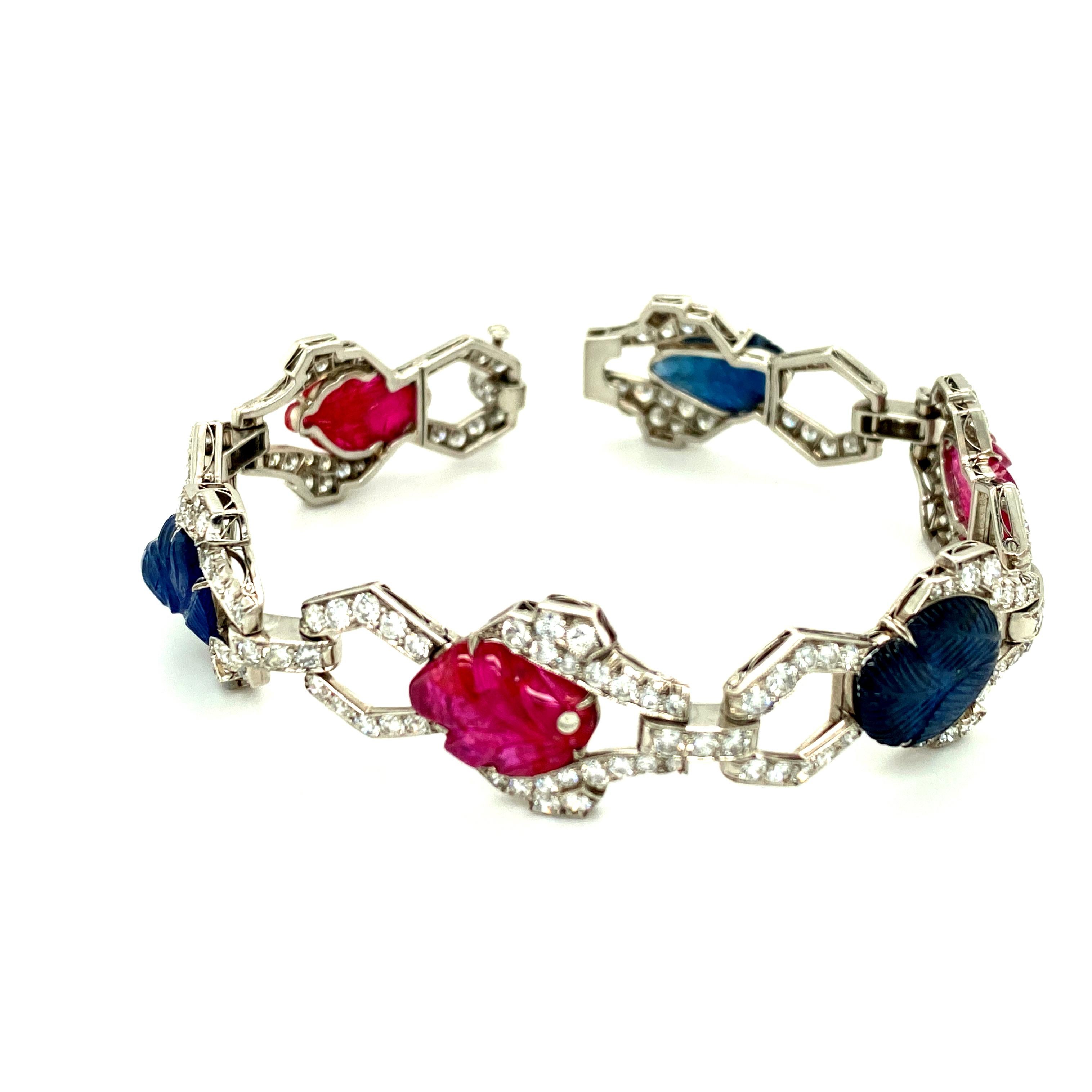 This Art Deco (1925-1935) Tutti Frutti platinum bracelet pairs approximately 6cts of round brilliant diamonds with an estimated 18cts of cabochon rubies and sapphires carved to resemble leaves.  The bracelet's design alternates the symmetrical links