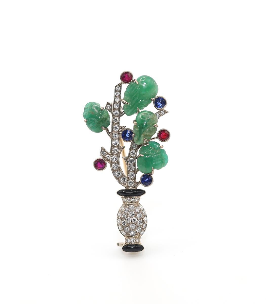 Incorporating Diamonds, Carved Emeralds, Rubies, Sapphires, and Onix to create a fine vase with flowers. Delicate and beautiful, it perfectly reflects its era. It is a significant design statement from a historic point of view. 
 
Art Deco style