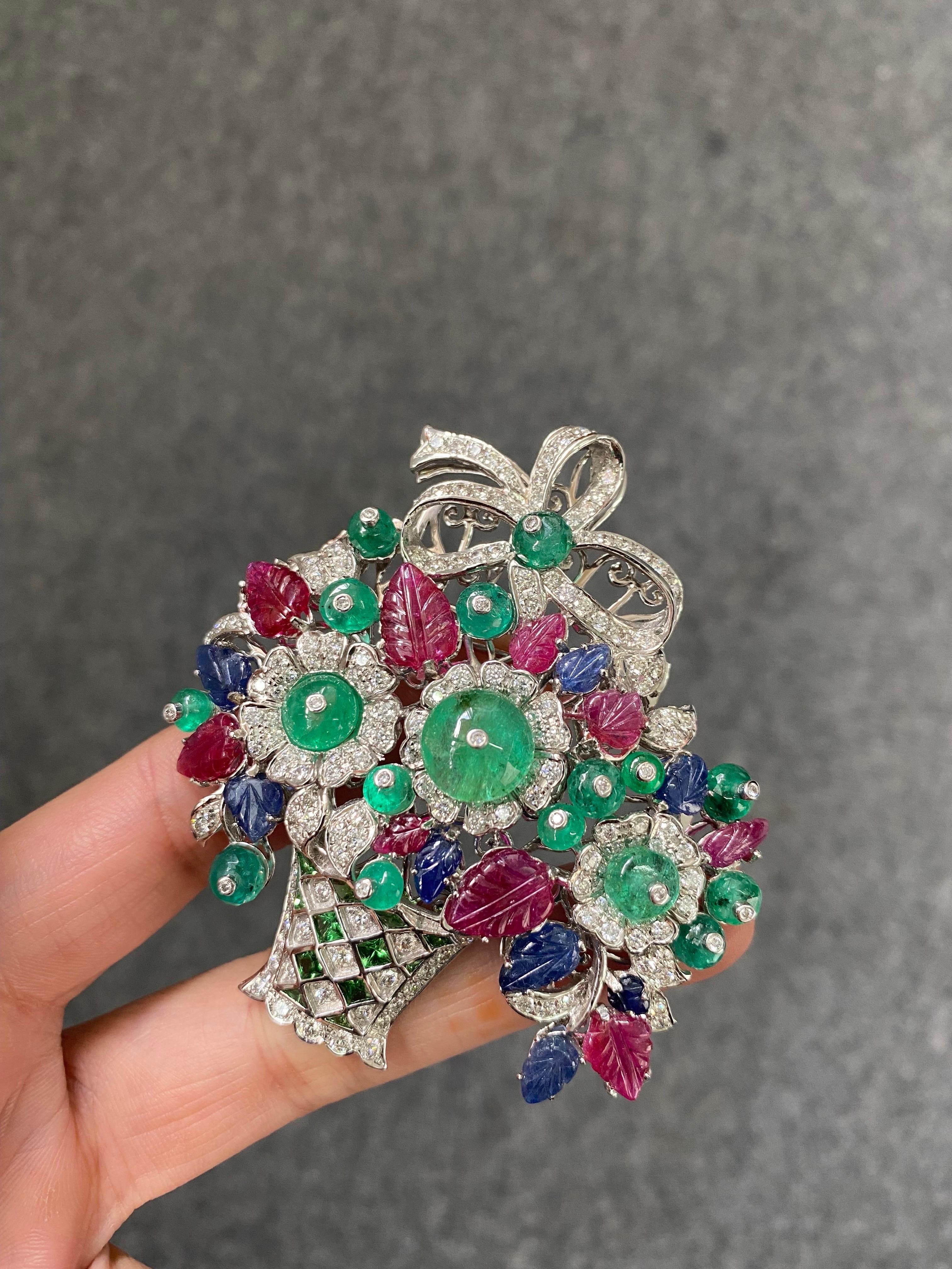 A beautiful art-deco inspired tutti frutti brooch depicting a flower vase, with 10.70 carat natural Ruby, 5.49 carat natural Sapphire and 18.05 carat natural Emeralds with 4.3 carats of White Diamonds all set in solid 18K White Gold. 
We provide