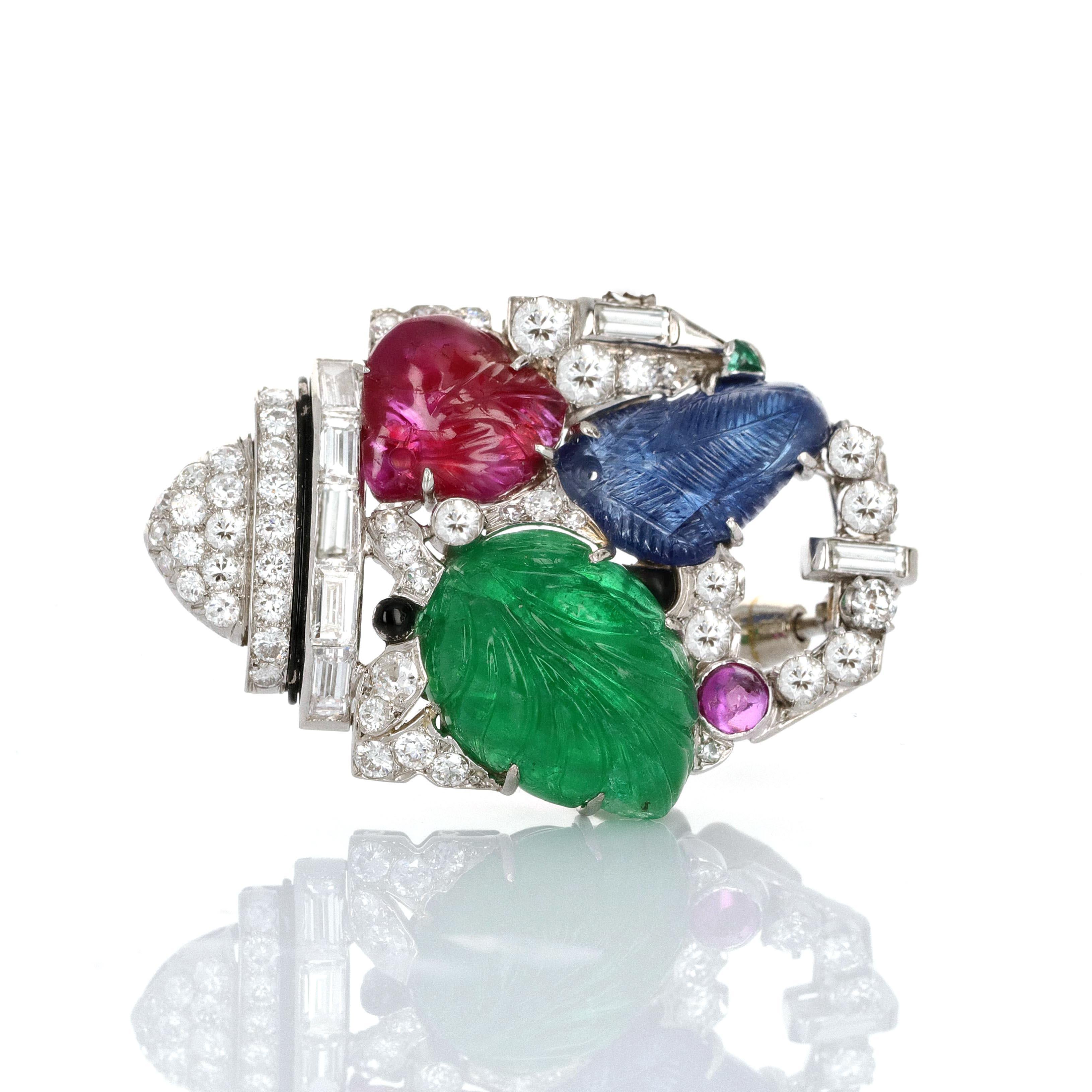 Art Deco Tutti Frutti style brooch with carved Ruby, Sapphire, Emerald, and Diamond made in platinum. There are 1.25 carats total weight in round brilliant diamonds and 0.50 carats in baguette shaped diamonds. Tutti frutti style, ruby, emerald,