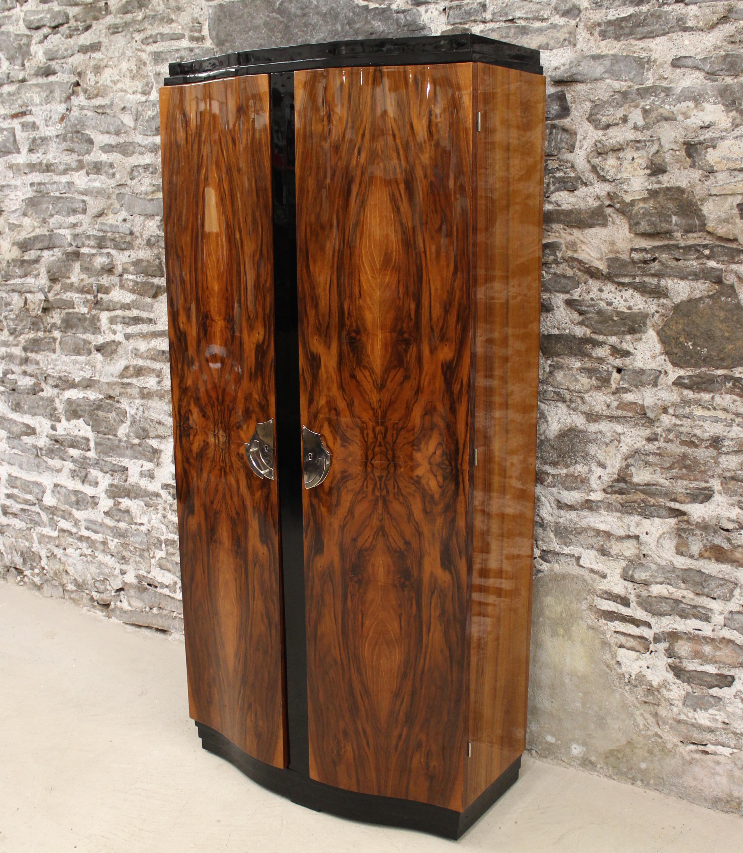 This Art Deco two-door armoire features ebonized trim on bow front, high gloss walnut doors and frame. It is done in the manner of Emile Jacques Ruhlmann.