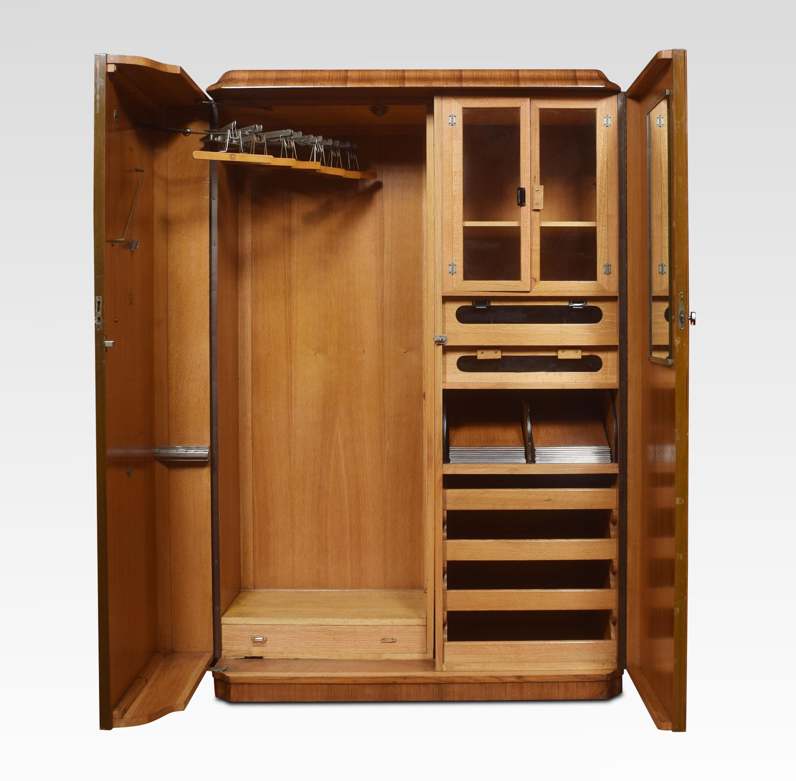 Walnut Art Deco compactum wardrobe, the moulded cornice above two large doors with Bakelite handles, opening to reveal fitted glazed compartments, drawers and hanging space. All raised up on a plinth base.
Dimensions:
Height 75.5 inches
Width 50