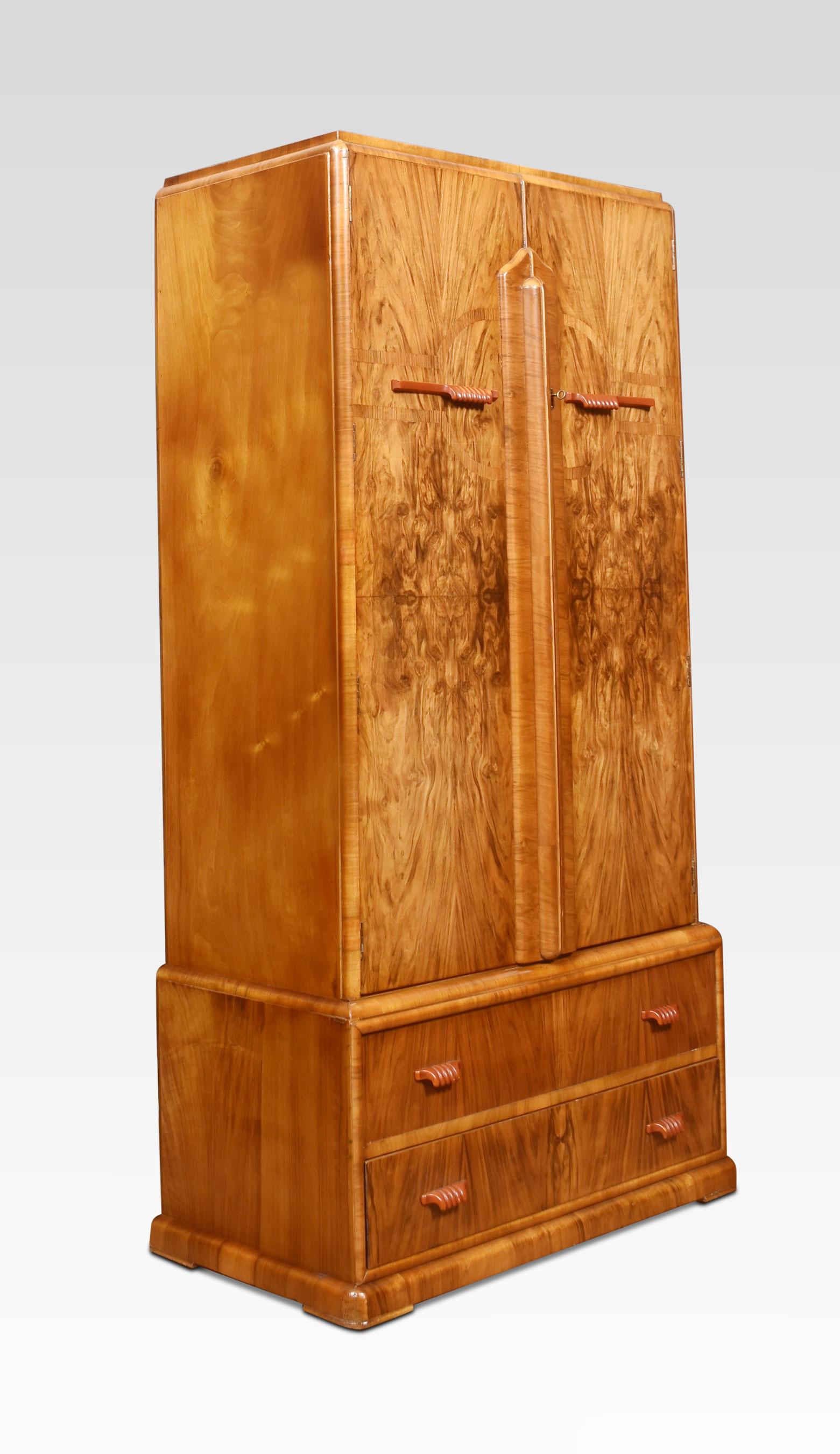 Art deco wardrobe of small proportions, the moulded top above two figured walnut drawers with bakelite handles, opening to reveal fitted interior. The base section is fitted with two drawers with similar bakelite handles. All raised up on a plinth