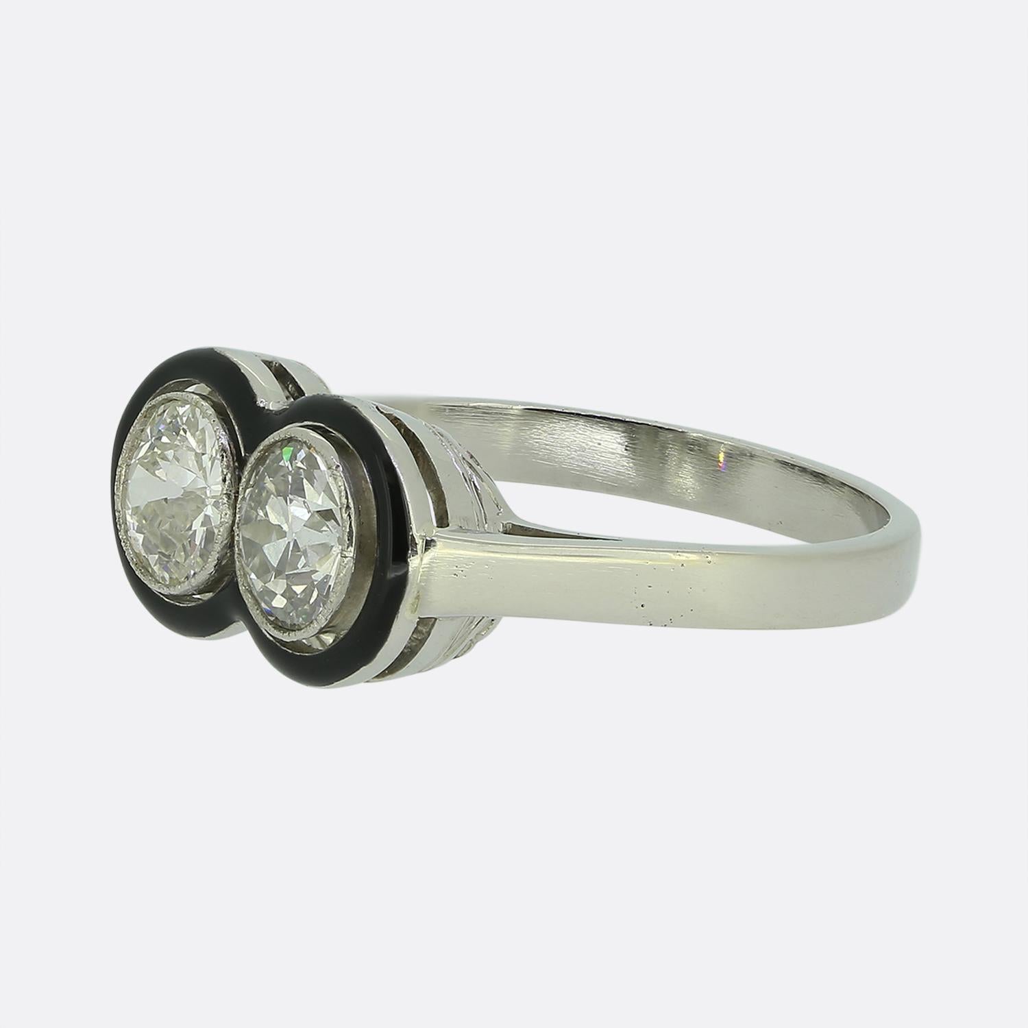 Here we have a stunning two-stone diamond ring crafted at a time when the Art Deco style was at the height of world design. A duo of round faceted old cut diamonds have been finely milgrain set atop a solid black enamelled backdrop which follows the