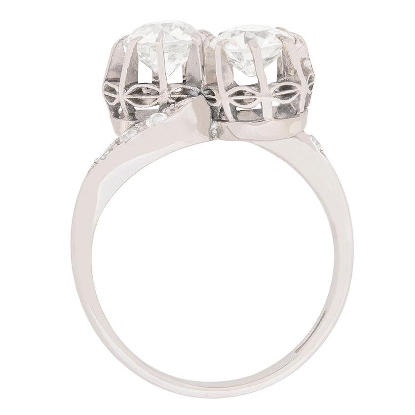 Cette magnifique bague torsadée est ornée de deux diamants identiques de taille ancienne au centre. Chacun pèse 0,90 carat, a une couleur estimée entre G et H et un degré de pureté de VS2. Ils ont été sertis dans des pinces, qui sont surélevées pour