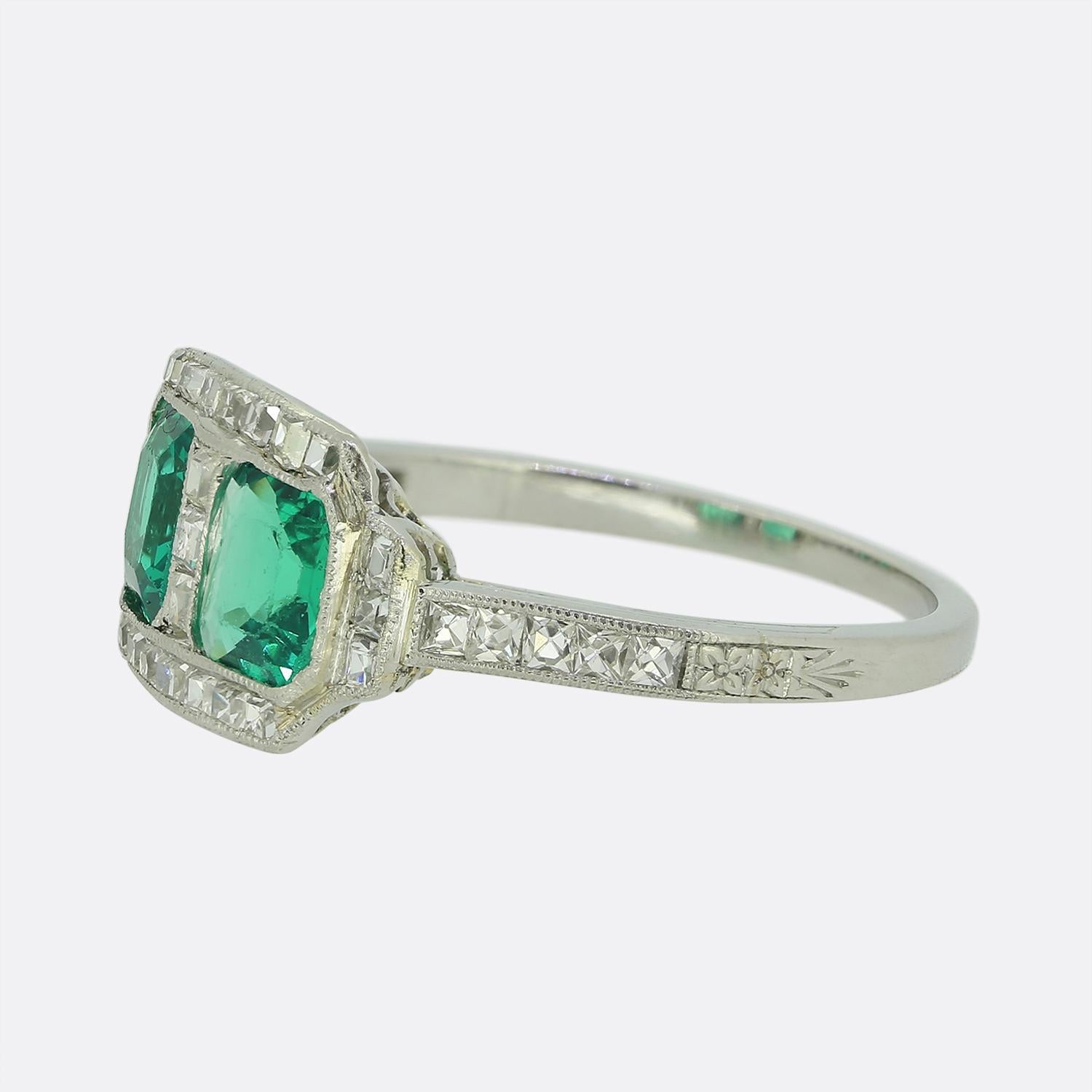Here we have a sensational Art Deco two-stone ring features a duo of striking asscher-cut green emeralds, set side by side. The emeralds are framed by a series of old asscher-cut white diamonds within a fine milgrain bordering creating a captivating