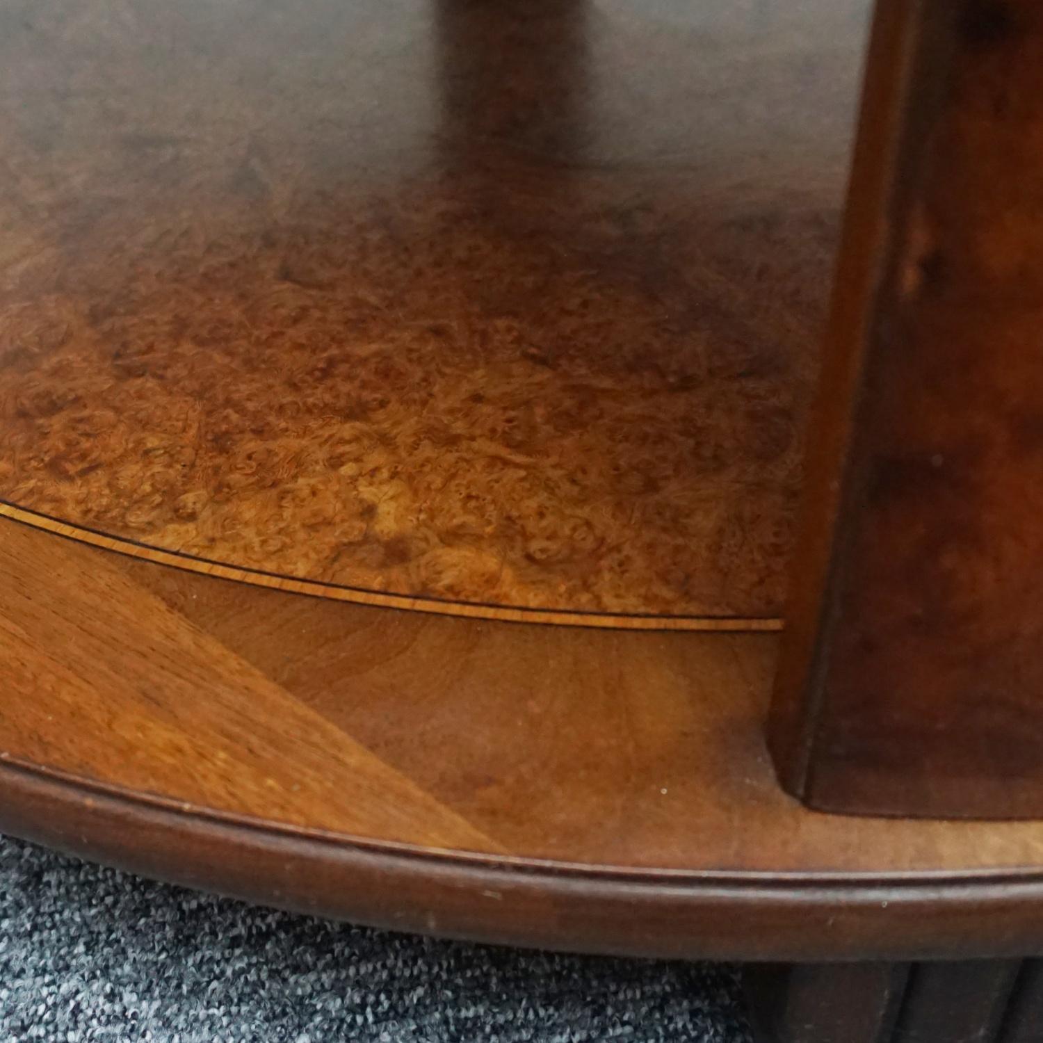 Zweistöckiger Art Deco-Mitteltisch. Massives Nussbaumholz mit Wurzelholz und gemasertem Nussbaumfurnier. Obere Tischplatte mit Kugeltrennwänden über detailliert gestuften Sockeln, die zu einer abgerundeten zentralen Tischplatte führen.