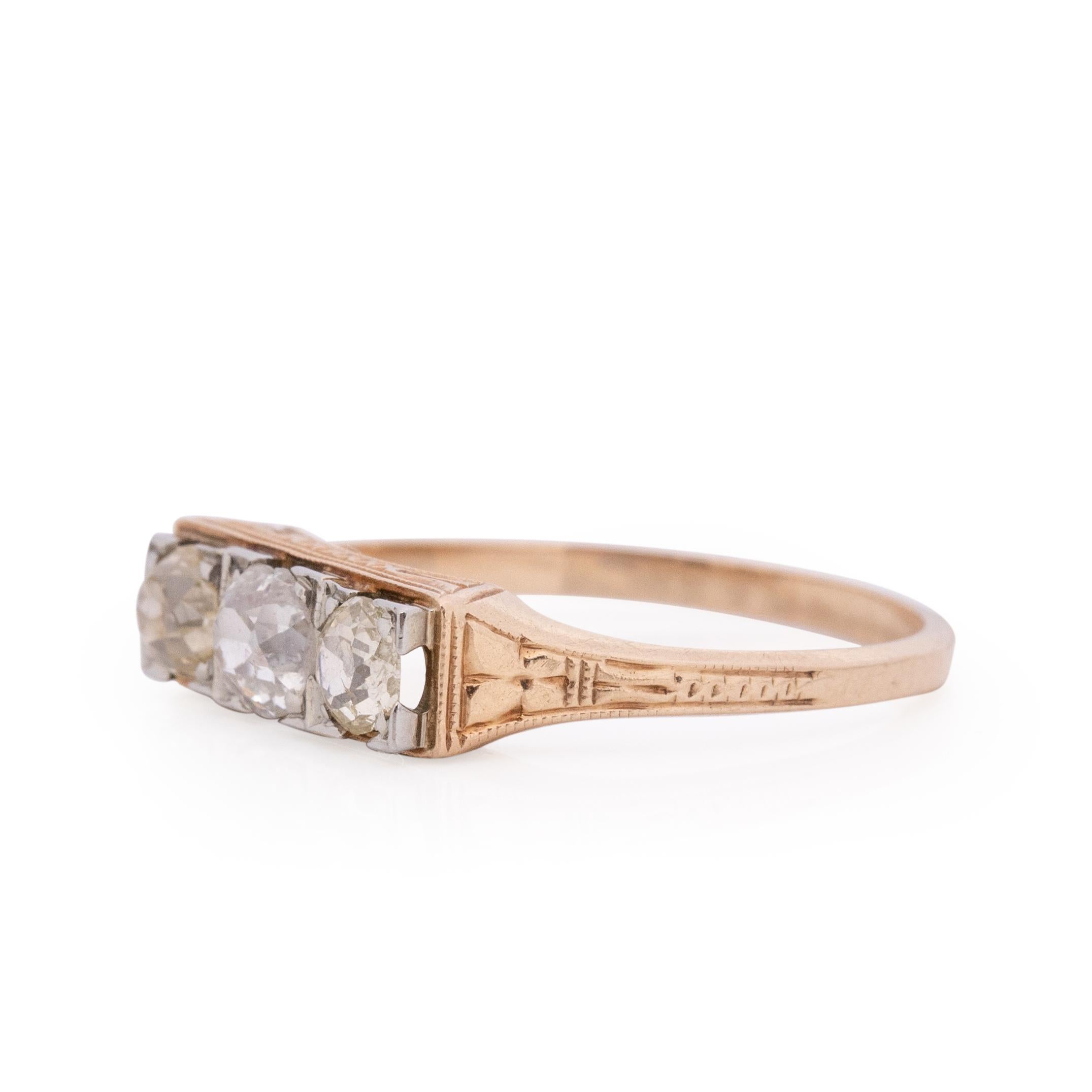 This three stone beauty is a true work of art. The chunky cut diamonds sit in white gold prongs, the gallery is held up by hand engraved yellow gold. The geometric design along the top reaches about half way done the shank, adding beautiful delicate