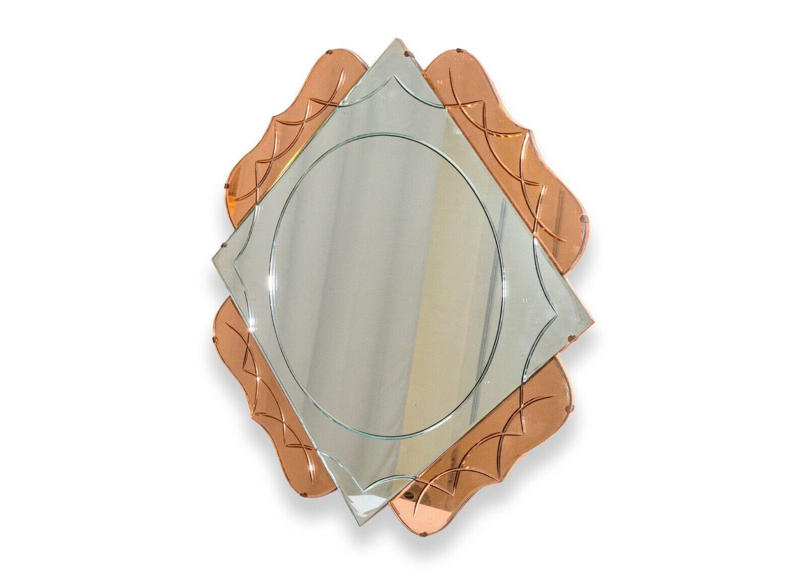 An art deco two tone pink hanging mirror. This is a very unique accent mirror. This piece features a mostly square design with rounded accents to the diamond shape. This mirror is wall hanging via a chain attached to the wooden frame on the