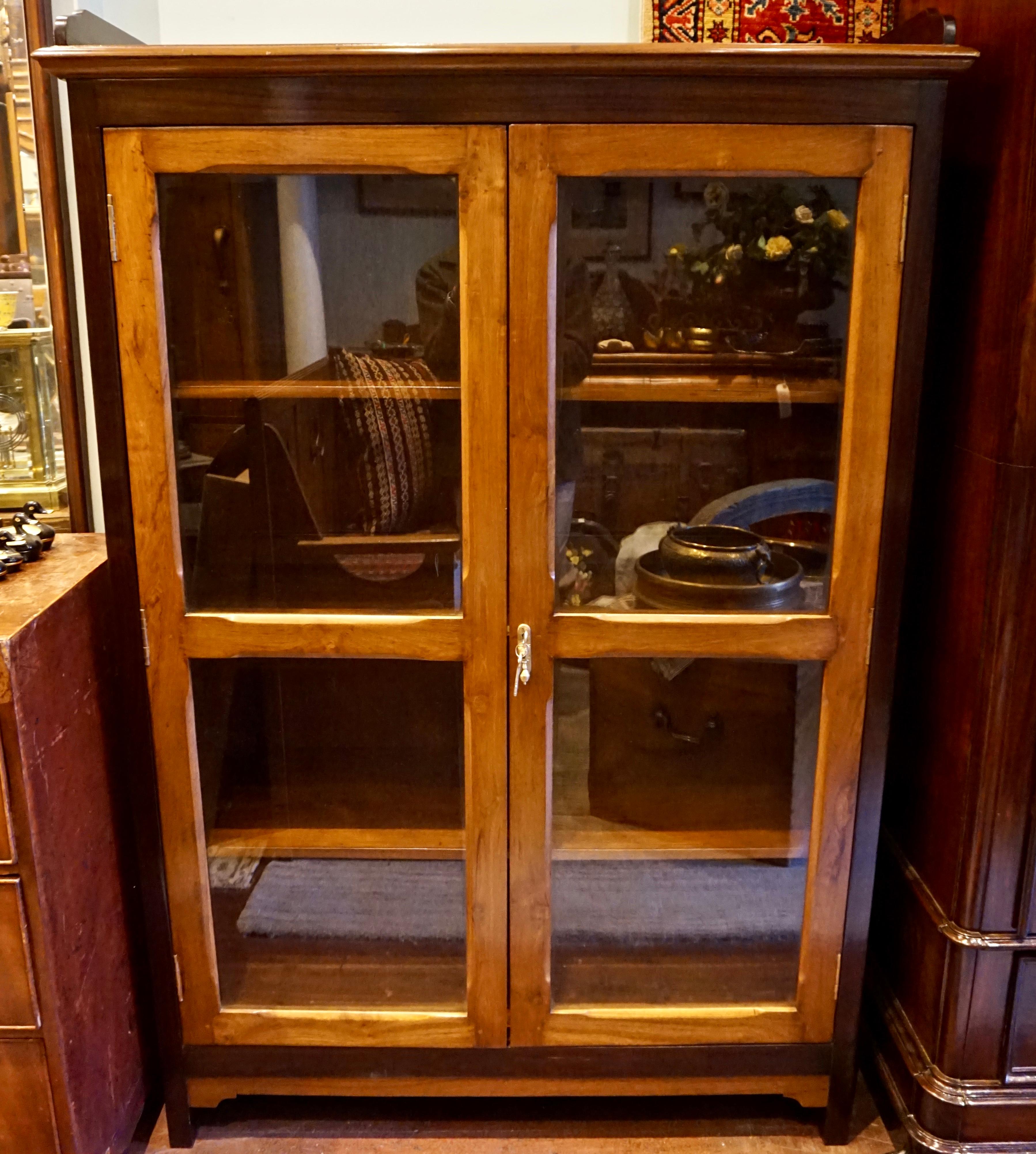 Circa 1930-35

Solid, refined two tone hand crafted teak and rosewood showcase/bookcase cabinet with sturdy teak removable shelves and locking doors. Renewed hardware. Peg work joinery. Versatile.