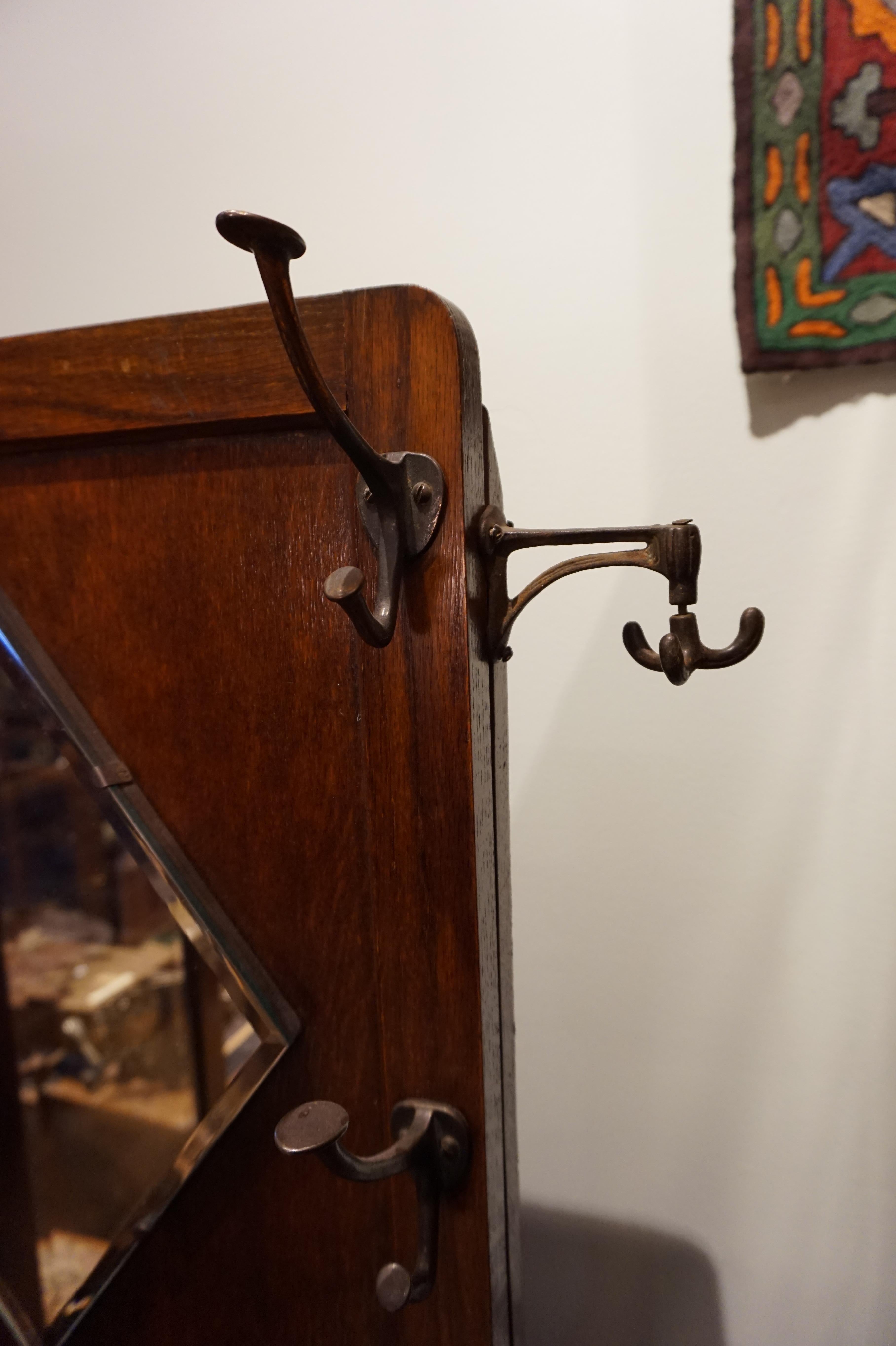 Quarter-sawn oak umbrella stand with bevel mirror, original hardware and metal trays including custom side extension hardware for scarves and coats. Utilitarian construction with clean lines and compact size,

circa 1935.