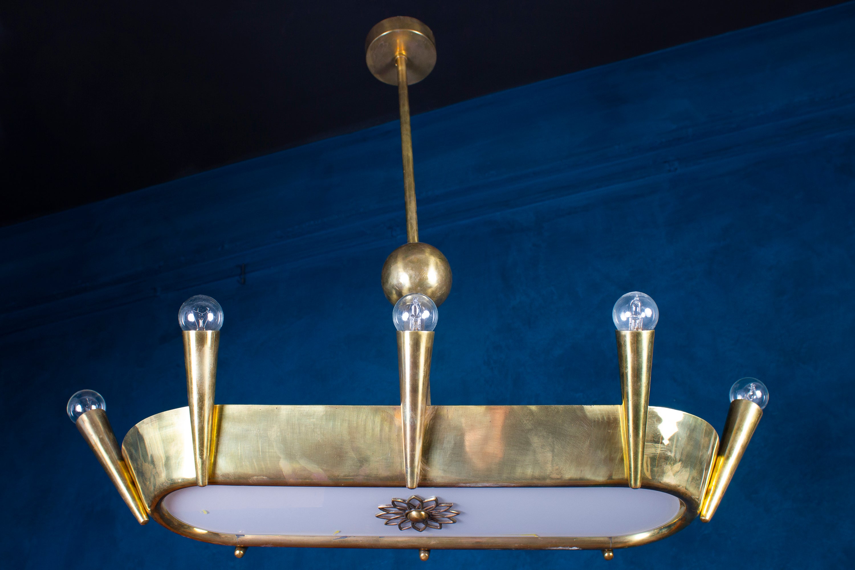 Insolite lustre Art Déco de forme ovale en bronze centré par un verre opalin avec huit supports de lumière coniques avec 8 ampoules E 14. Italie 1930'.
 