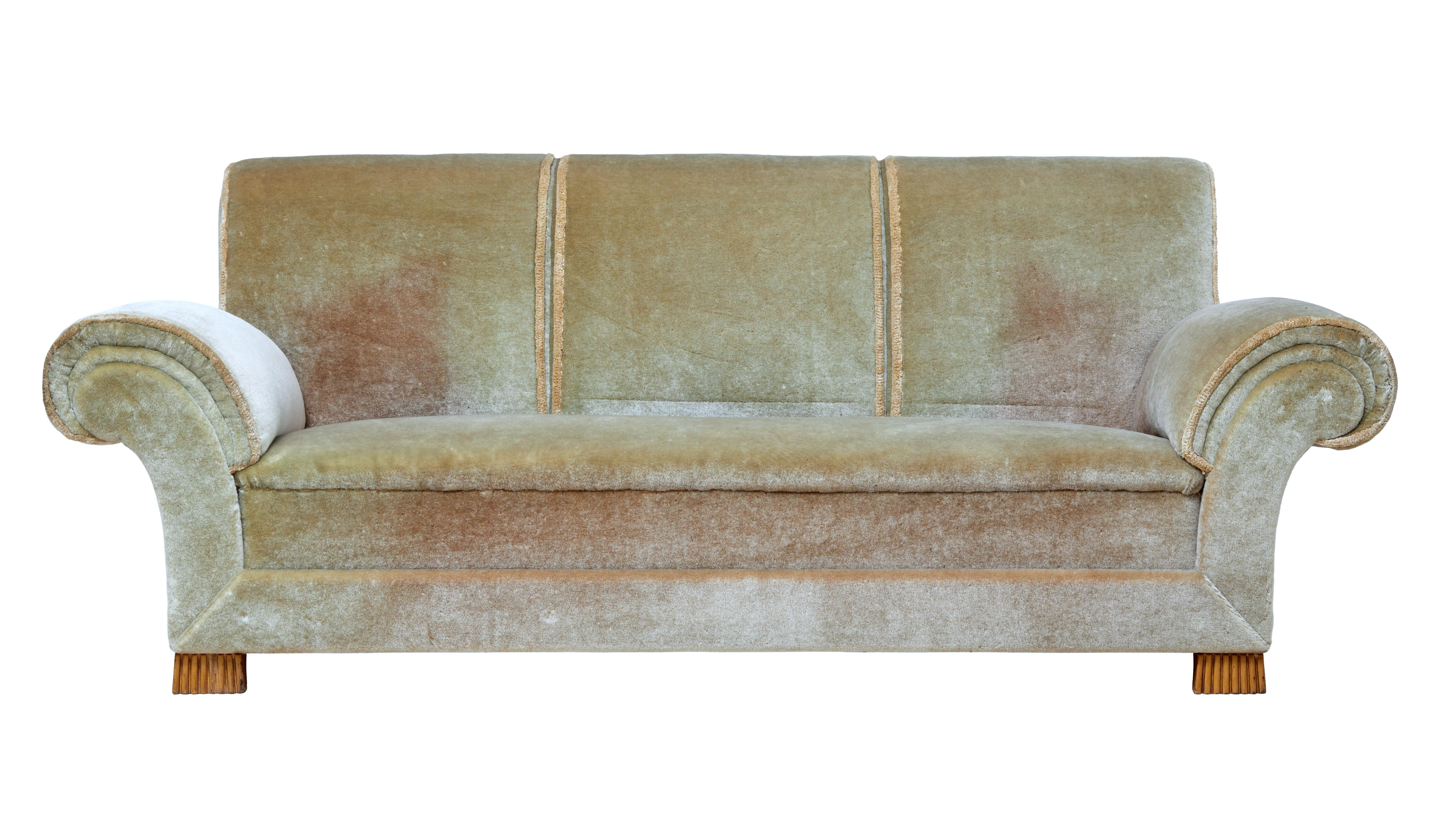 Here we have a living room suite comprising of a sofa and armchair, circa 1930.

Of grand proportions, with typical Art Deco flowing arms and scrolling back rest.

Upholstered in a thick green fabric which has become faded over the years, but
