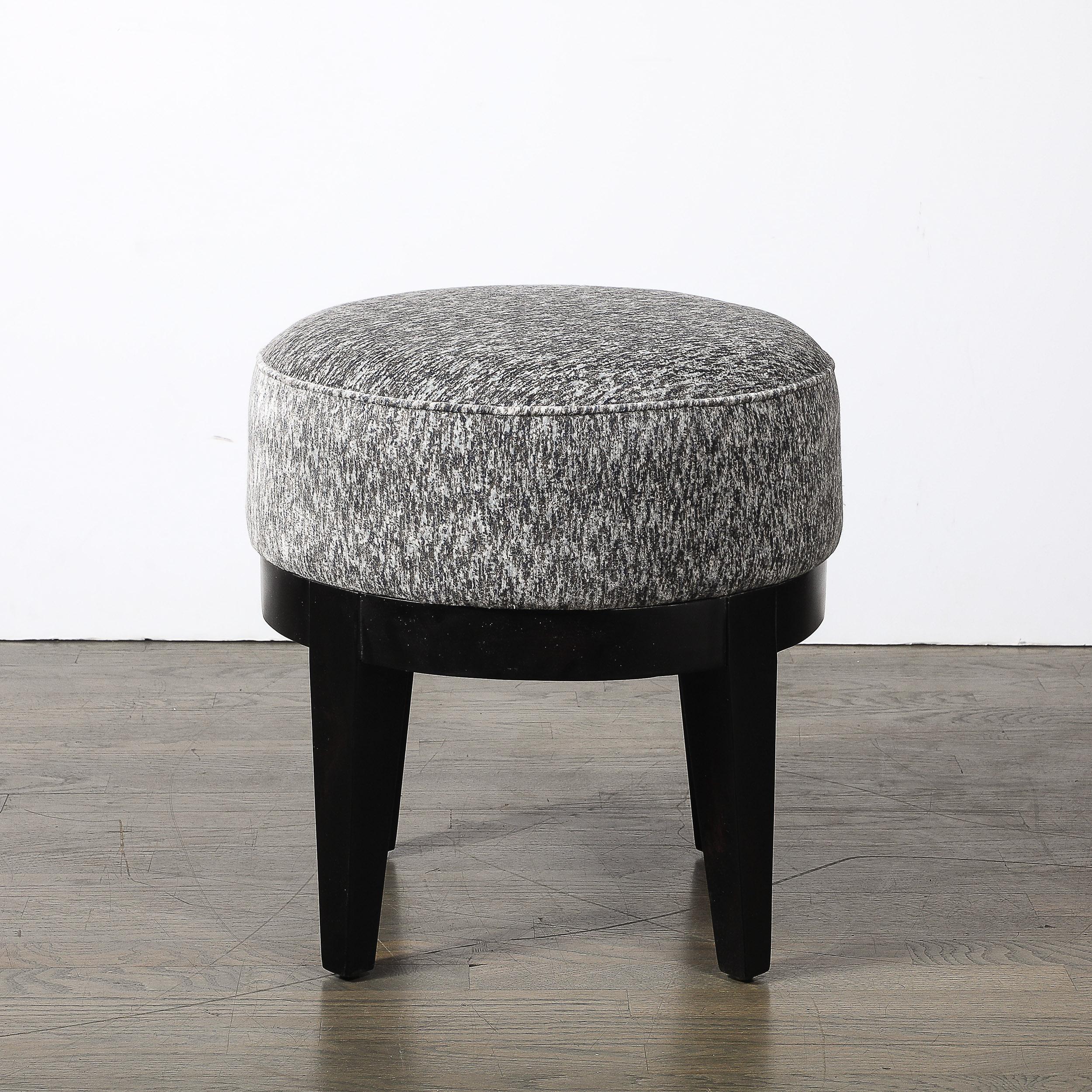 Dieser elegante Art-Déco-Hocker aus der Zeit um 1935 ist ein Beispiel für die Raffinesse und die stromlinienförmige Ästhetik dieser Epoche. Der Rahmen aus fein ebonisiertem Nussbaumholz zeigt reiche, dunkle Farbtöne mit einem tiefen, glänzenden