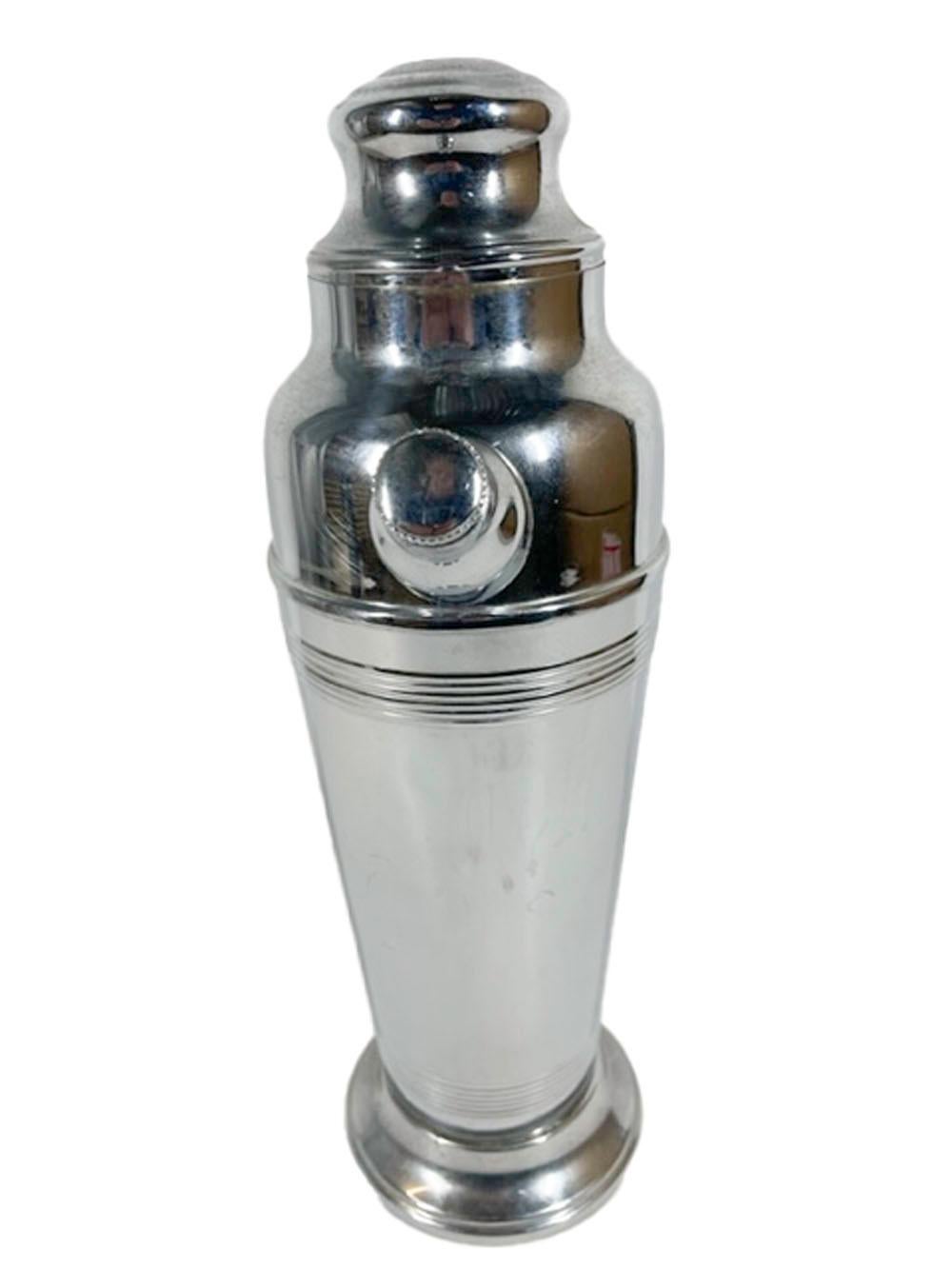 Art Deco chrome cocktail shaker with a translucent red Lucite handle. The urn-form body embellished with a reeded band just below the shoulder seam and another just above the stepped foot. Marked on the bottom in circular text 