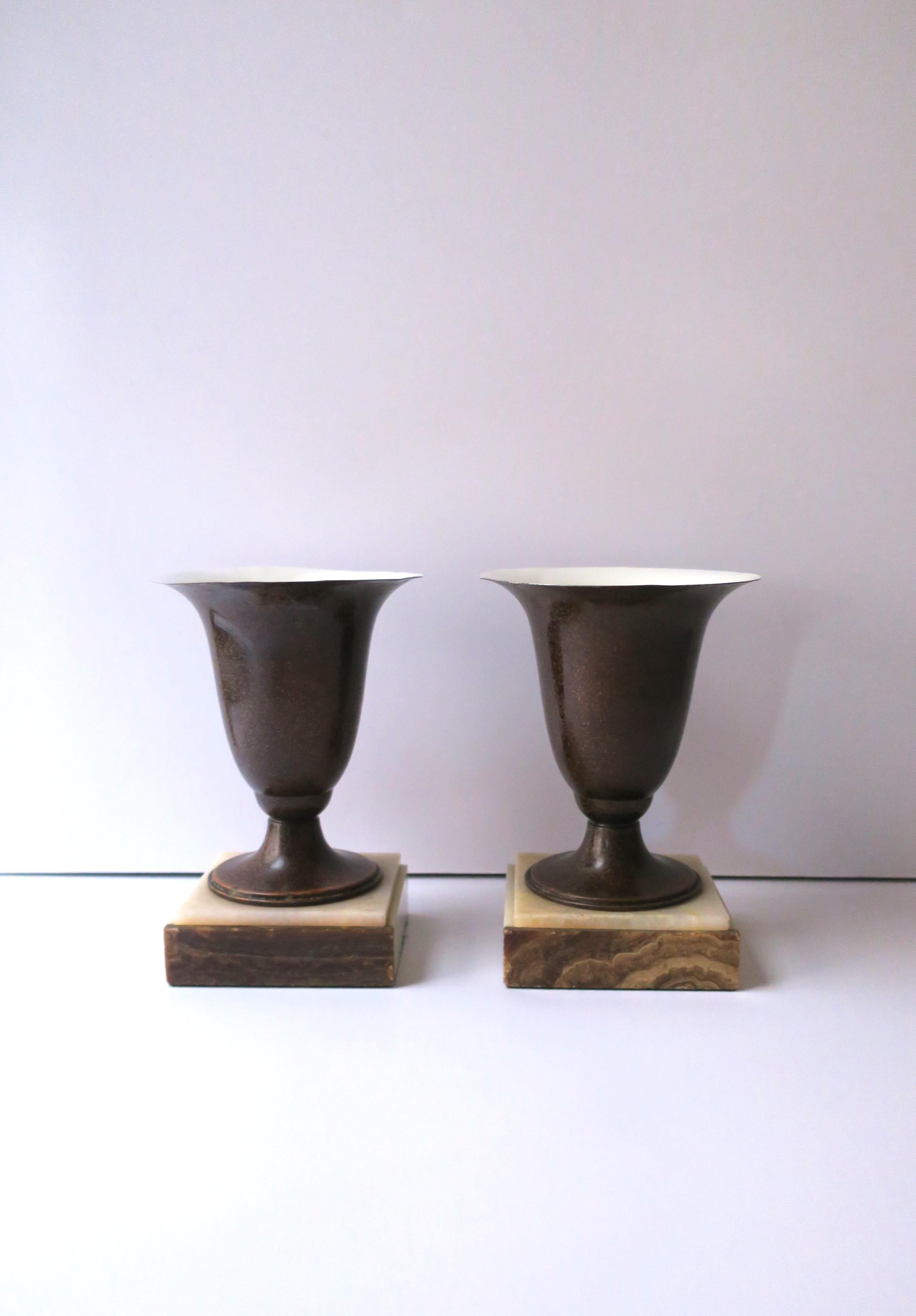 A pair of enamel and onyx marble urn form table lamps of the Art Deco period, circa early-20th century. Urn form has a rich brown exterior enamel, interior is an off-white. Bases are a coordinating onyx marble with brown on the front an off-white