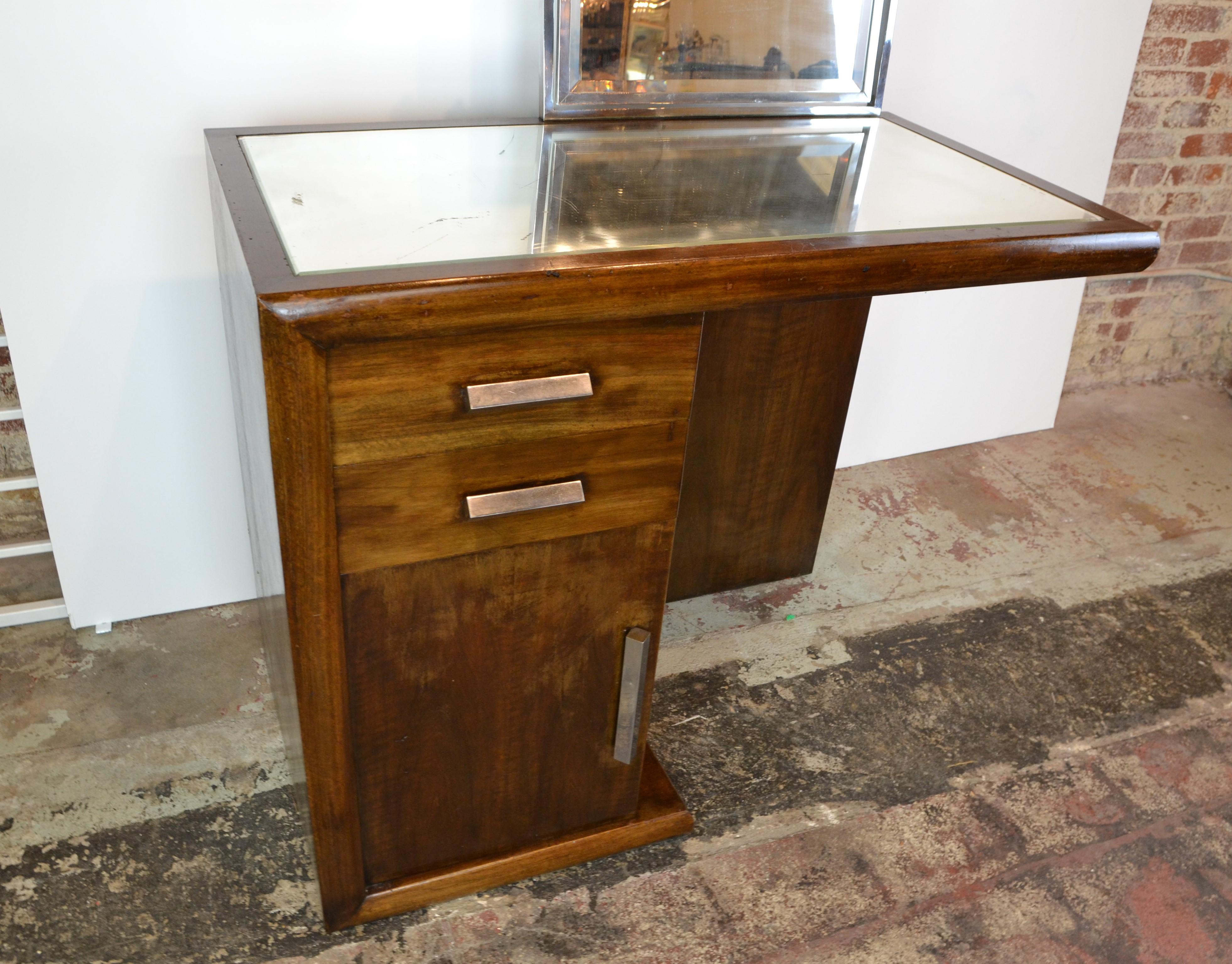 A genuine Art Deco vanity / dressing table in mahogany. Chrome hardware and mirror surround. Inset mirror top. Features one cupboard and 2 drawers. circa 1935. The desk with out the mirror is 34.75