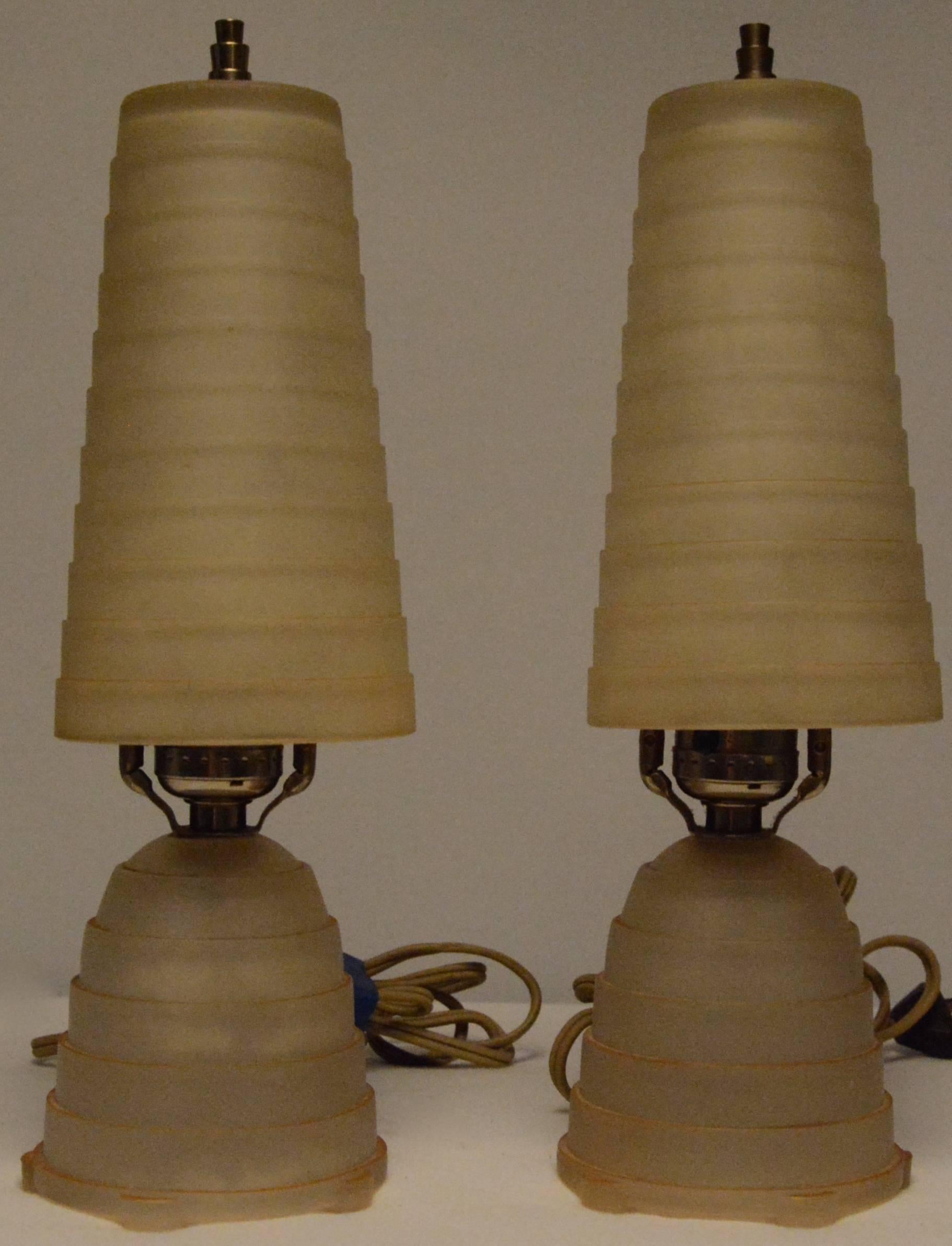 This is a nice pair of vintage Art Deco vanity lamps. They have soft gold frosted with stepped glass shades and matching base. Each lamp retains its original finial and takes a tubular bulb. The cords will need to be replaced as there is bare wire