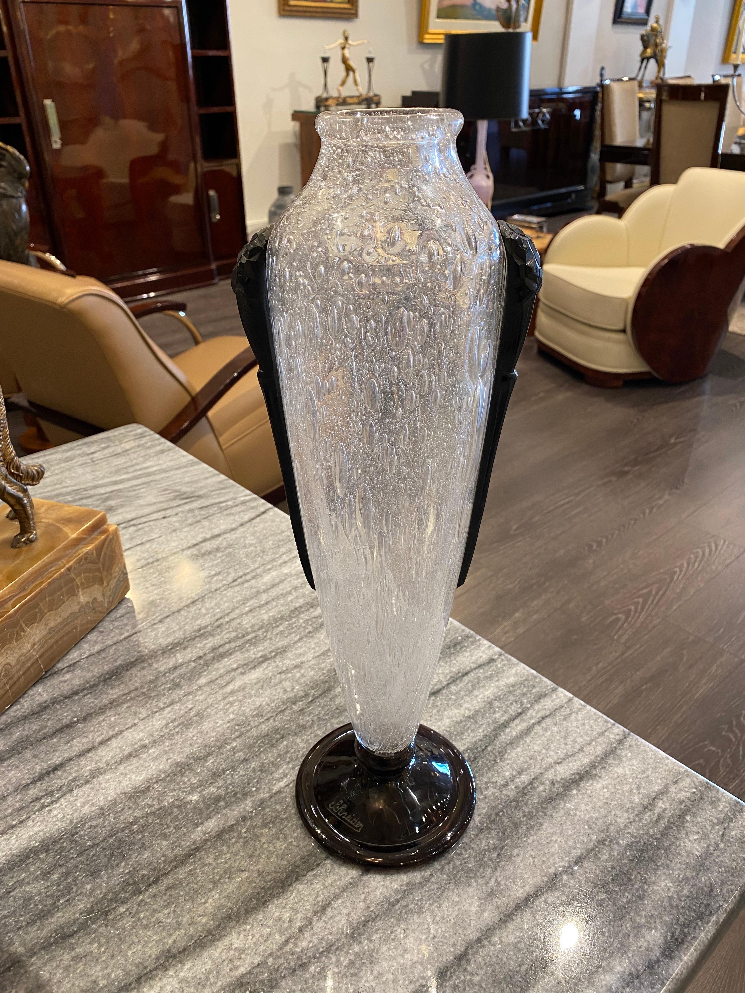 A cylindrical-shaped vase in Clear bubbled glass with wheel-carved Black glass handles/side applications.  This piece belongs to the Pluviose serie from Charles Schneider.
Signature: Schneider

This piece can be found on page 320 in the book of