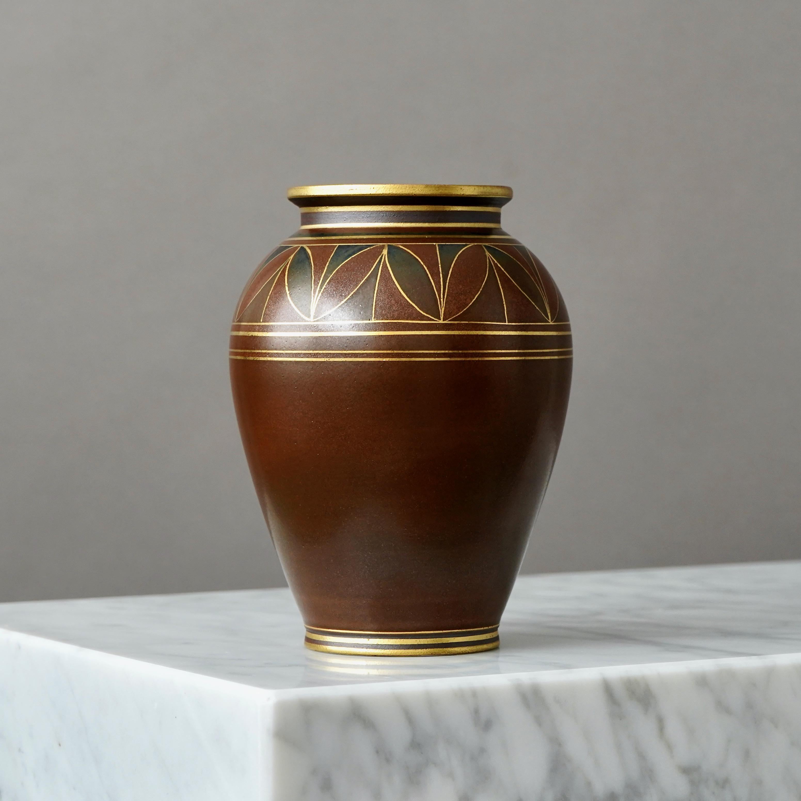 A stoneware art deco vase. Beautiful glaze with foot and mouth detailed in gold.
Designed by Gunnar Nylund for ALP (Lidköpings Porslinsfabrik), Sweden, 1930s.

Good condition, but with a dark spot in the glace from the production (pictured).
Stamped