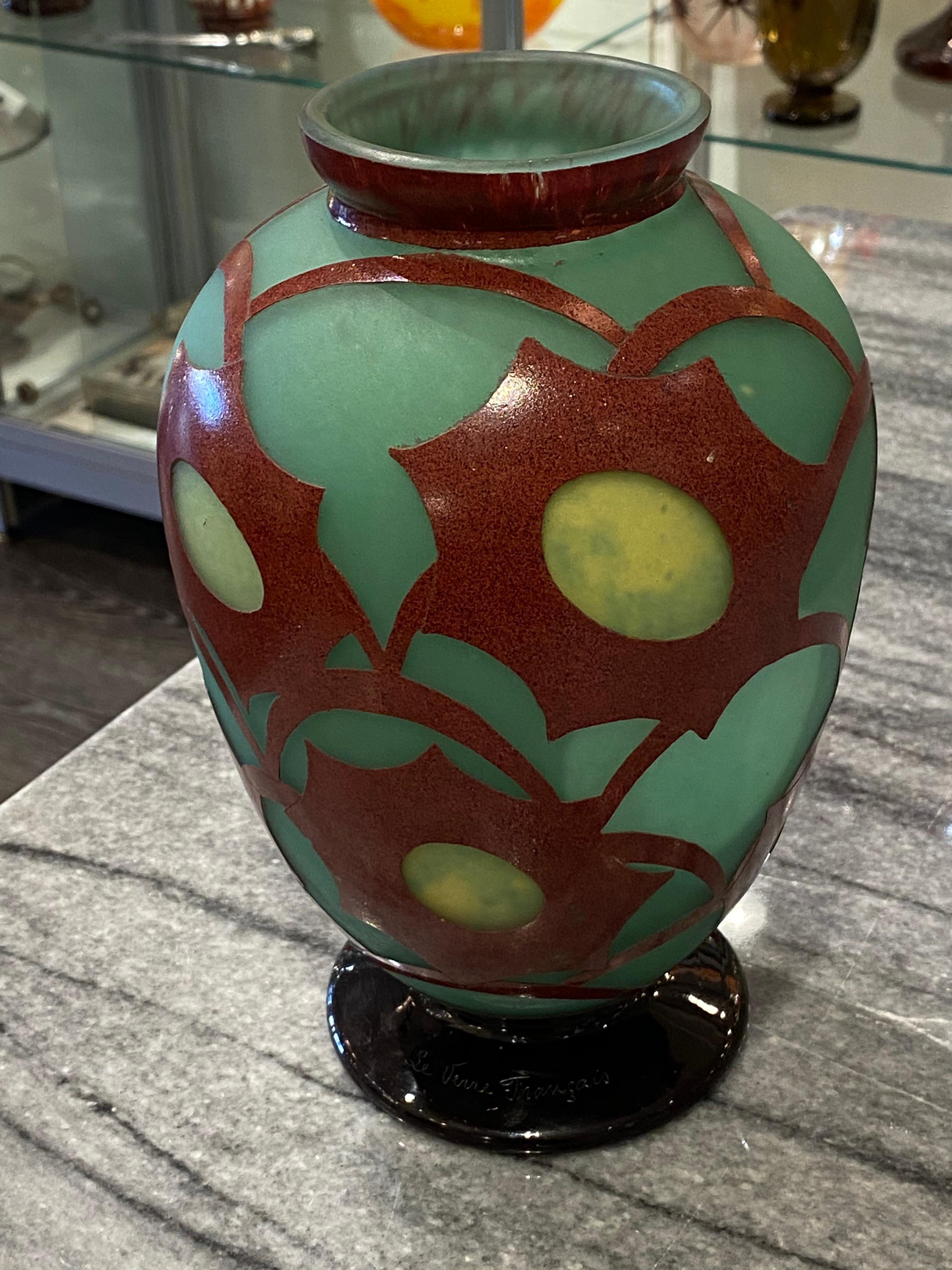 A vase in Green glass with Yellow spots (flower hearts), overlaid with Copper Red.  The pattern is acid-etched and it is from the Cosmo serie of Le Verre Français. 
Signature: Le Verre Francais.

Charles Schneider was a renowned glassmaker during