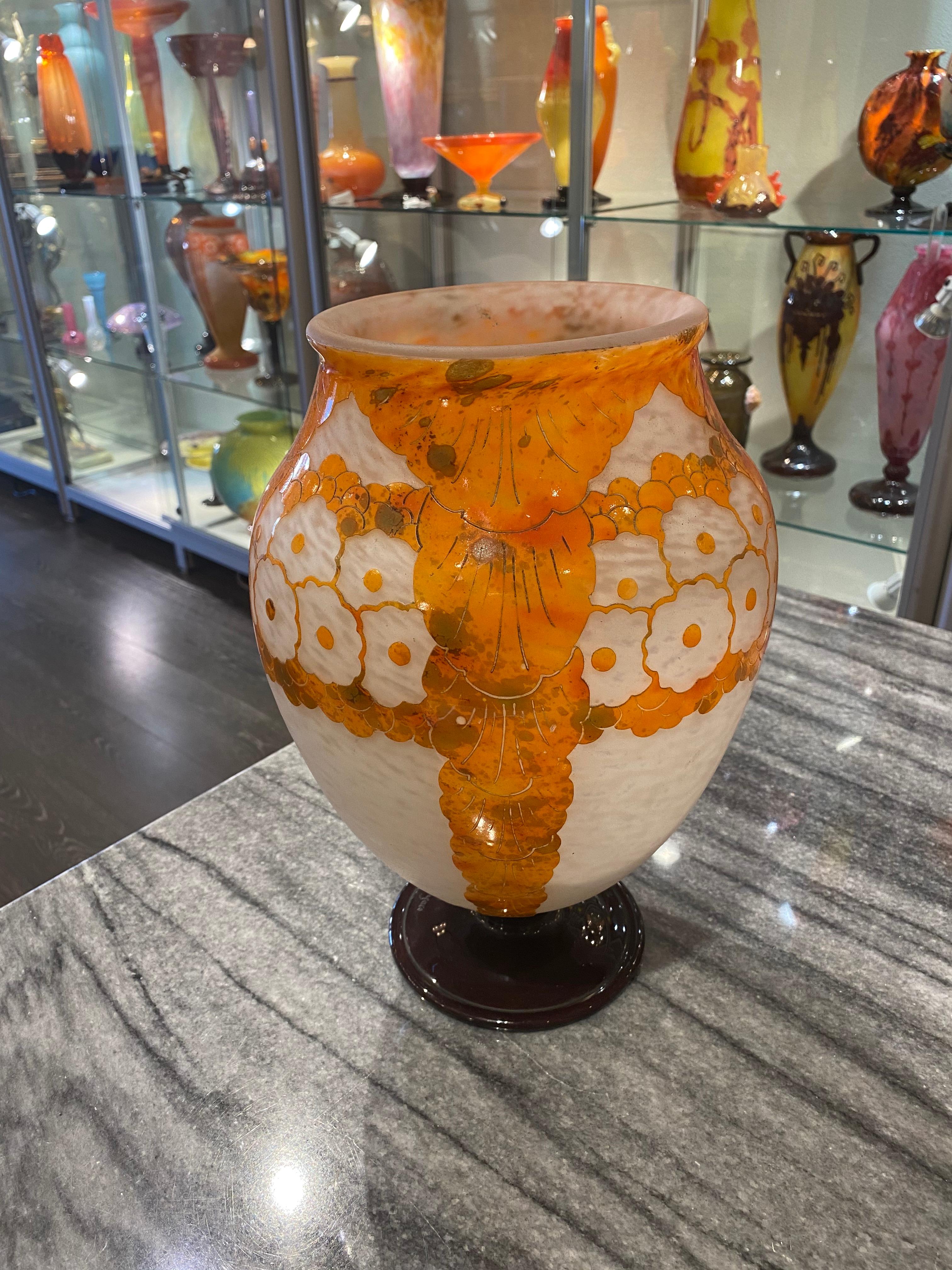 A round-shaped glass vase in Opalescent White overlaid with Mottled Orange, Red and Green.   The pattern consists in a wreath of small flowers that have hints of Oranges.  This motif is acid etched and it is from the Glycines serie of Le Verre