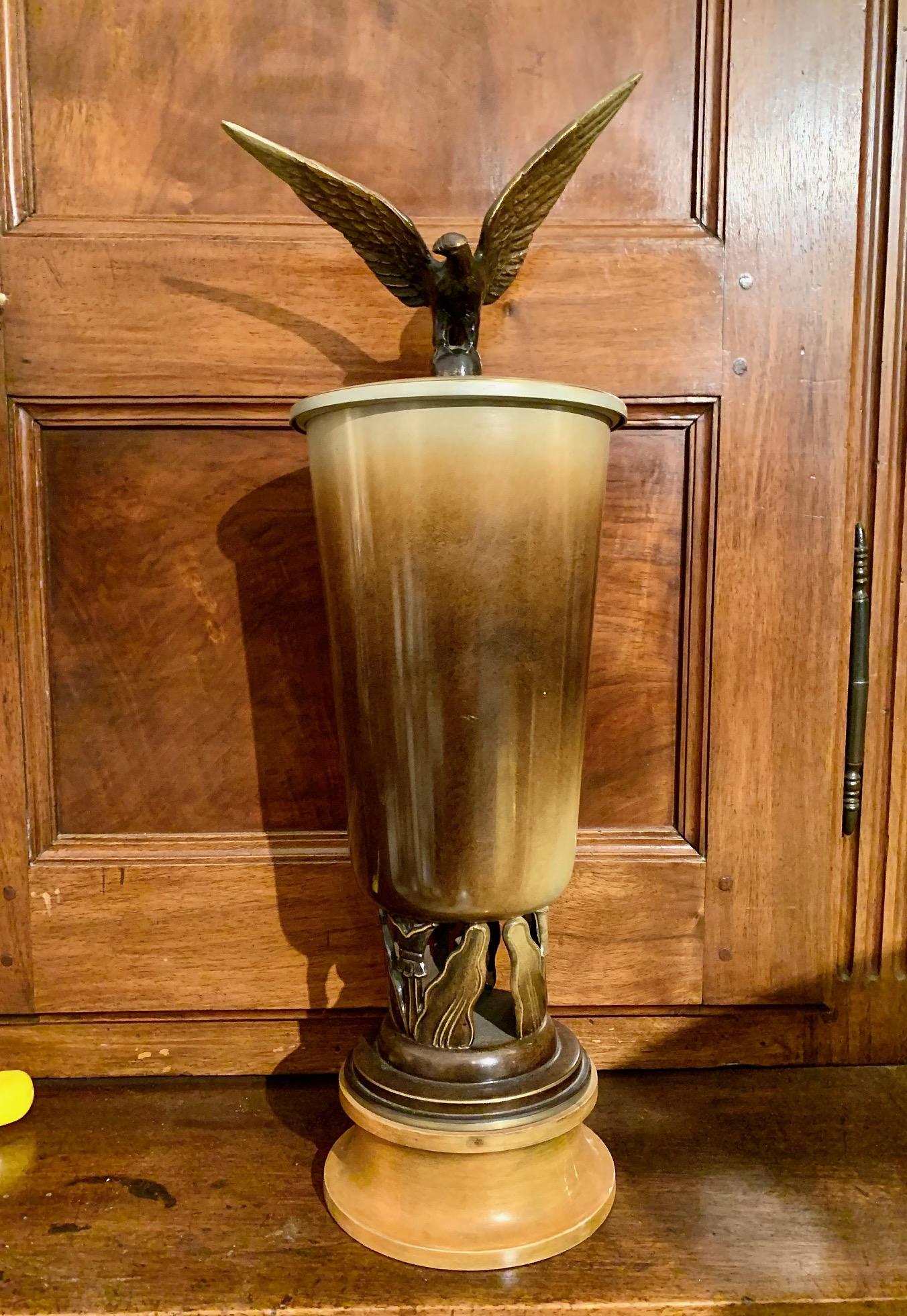 A vase with a Ystad Bronze metal lid, mounted on a wooden pedestal with vegetal decoration at the base, from where the glass emerges, finished with a lid with the figure of an Eagle.