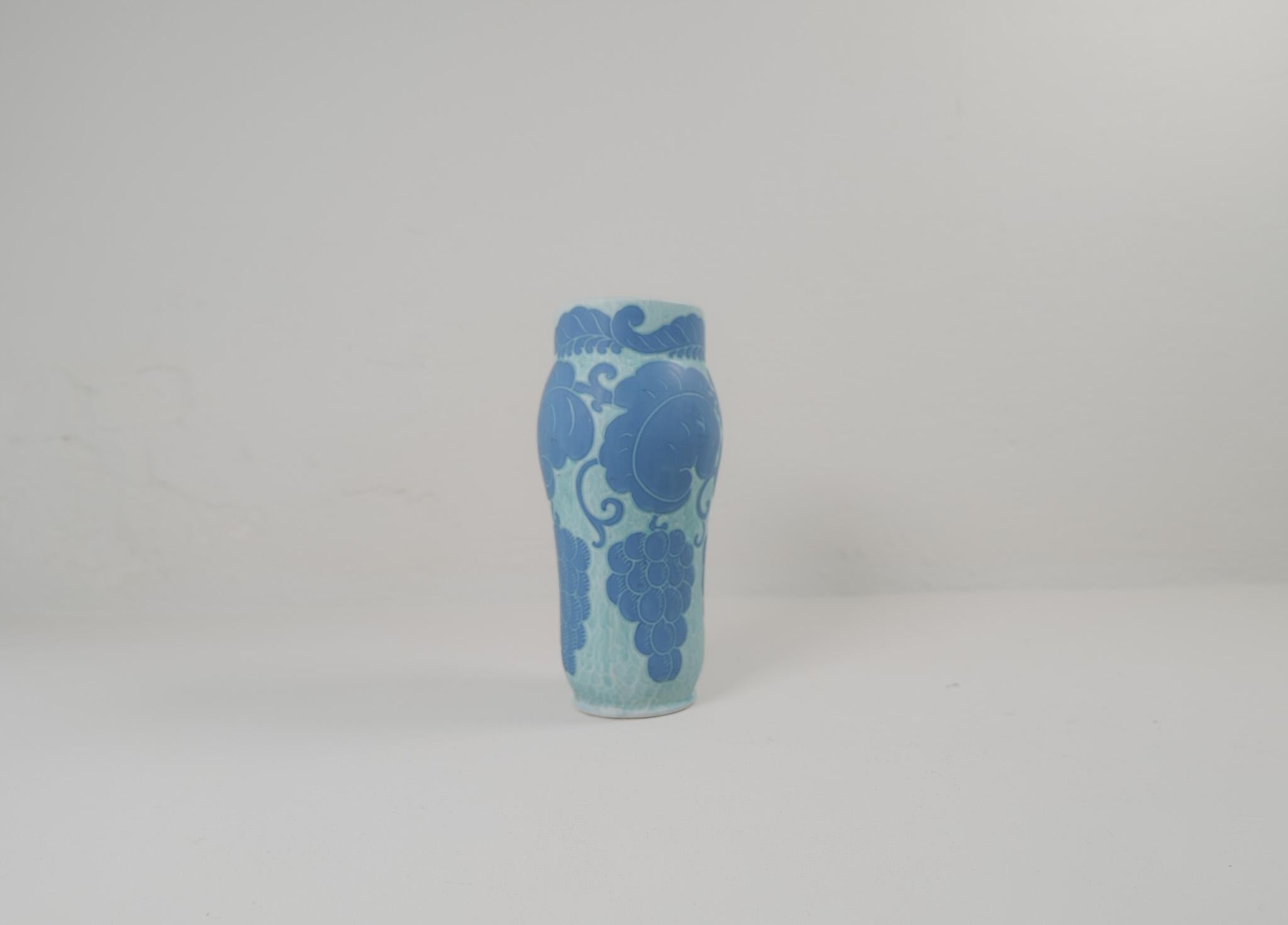 Sgraffito vase decorated with a floral/grape motif, by Josef Ekberg for Gustavsberg.
Sgraffito is a way of combining two layers into a pattern, the second layer is carved of, and left is a light blue background with a beautiful pattern on top.