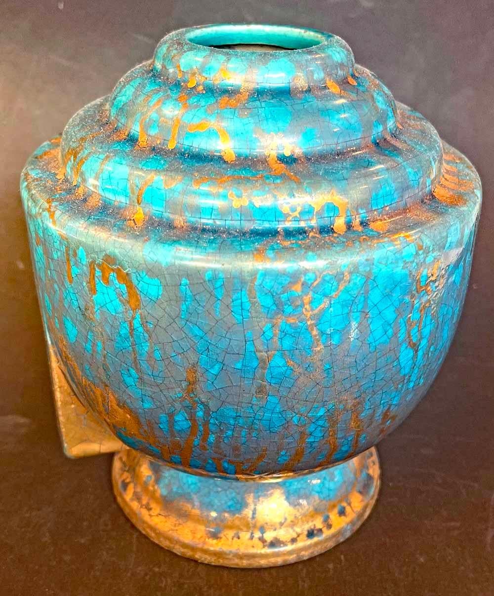 This classic French Art Deco vase demonstrates a major characteristic of the period -- a series of setbacks from its curving body to the neck above -- all brilliantly glazed in a Mediterranean blue-green with rich veining in gold. The piece was made