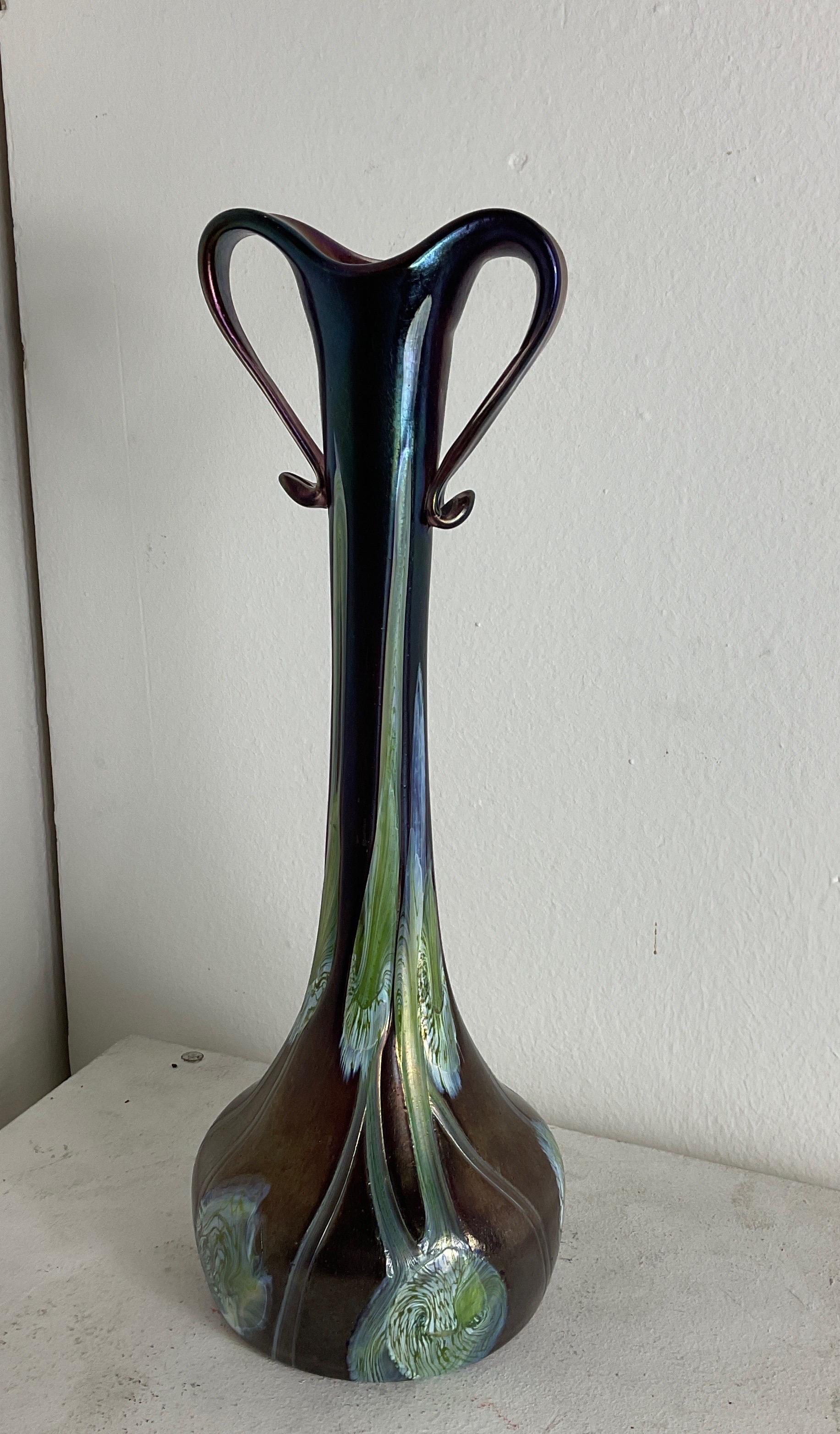 Vase mit zwei Henkeln, Robert Holubetz, Johann Loetz Witwe für E. Bakalowits Söhne, Dekor Olympia, ca. 1893 Diese Henkelvase besticht durch ihre schlichte und zugleich elegante Form. Wie der Stiel einer Blume, die aus ihrer Zwiebel herausragt,