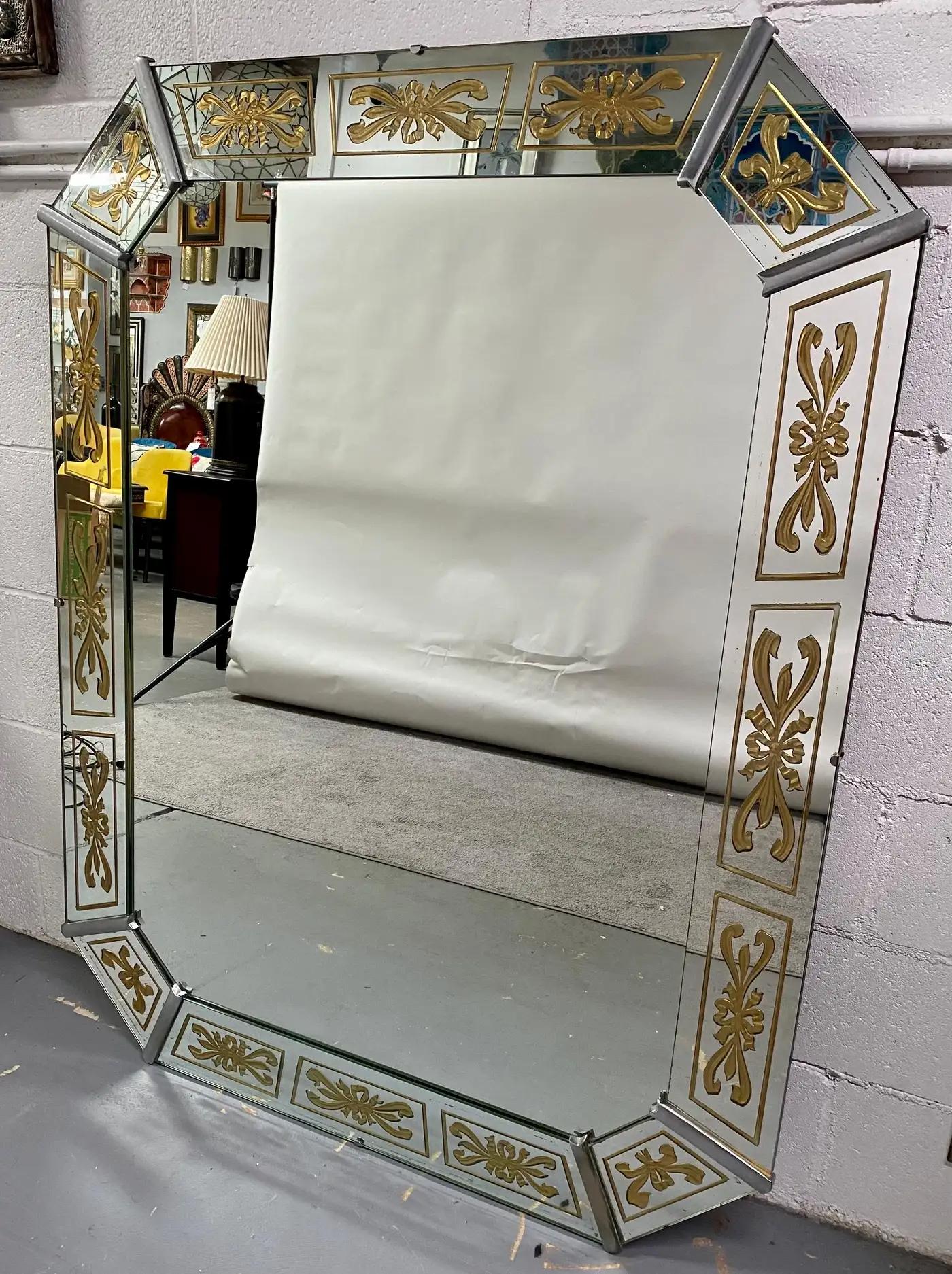 Un elegante espejo veneciano Art Decó de grandes dimensiones. El espejo tiene forma octogonal y es muy robusto y pesado. El marco está formado por 8 paneles individuales de espejo, cada uno de ellos está fina y artísticamente grabado en oro para