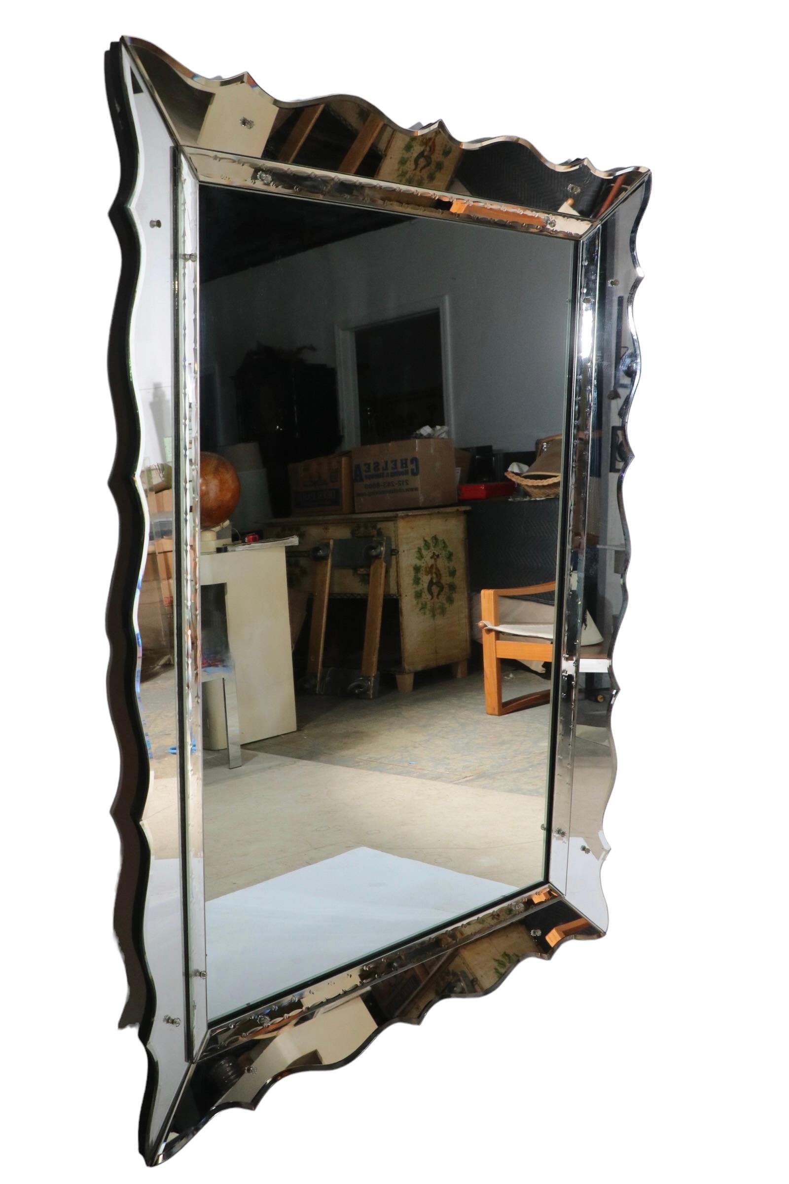 Glamorous High Style Art Deco, Hollywood Regency, Venetian style mirror in the manner of Marchand. This example features scalloped mirrored edging, and mirror trim which surrounds the rectangular interior mirror panel. The piece is in very fine,