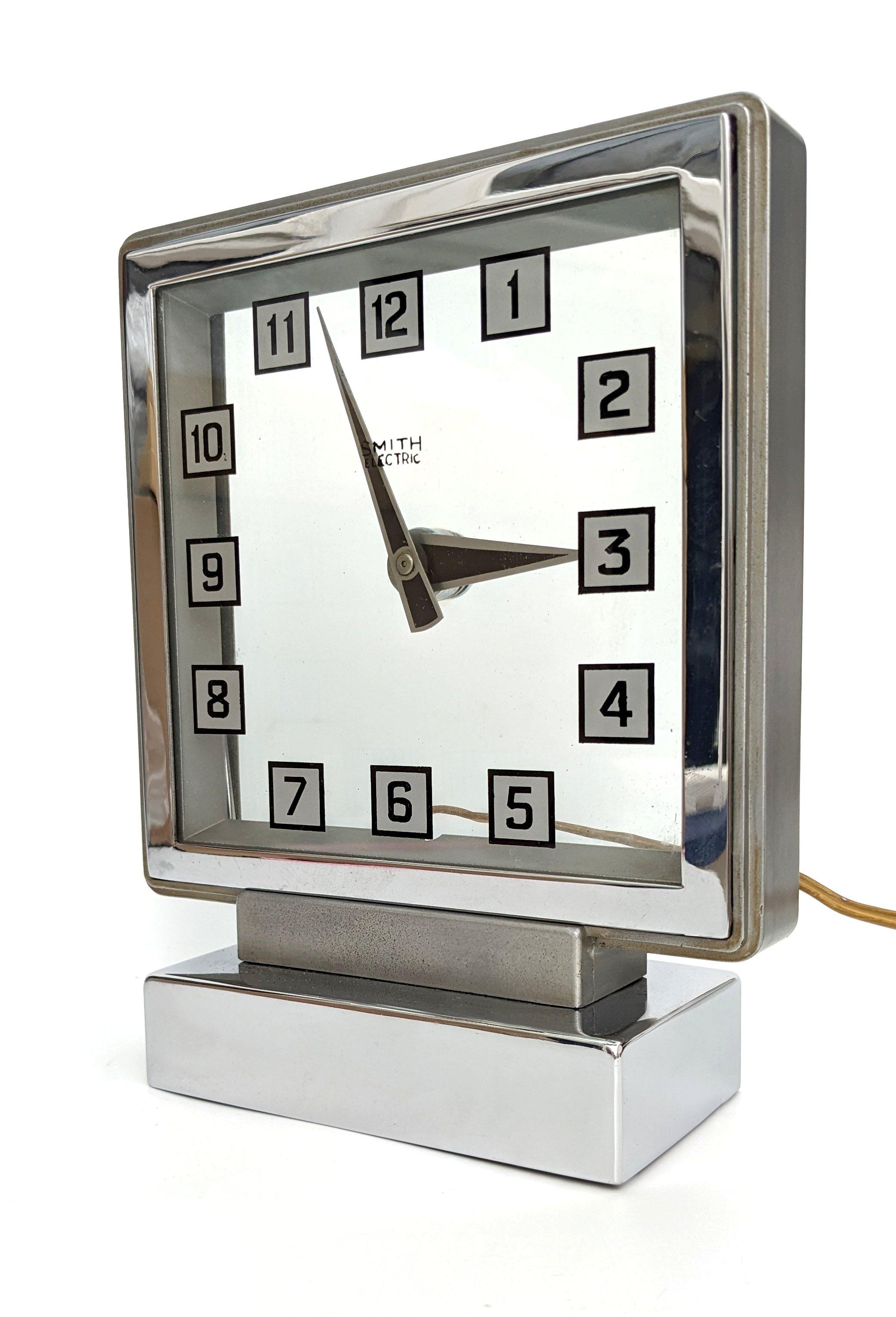 Nous vous proposons cette horloge mystère Smith, fabriquée par Smith's Electronic Clocks. Le boîtier chromé a été moulé en aluminium. Le verre présente des chiffres noirs sur un fond carré argenté avec une bordure noire. La vitre arrière contient