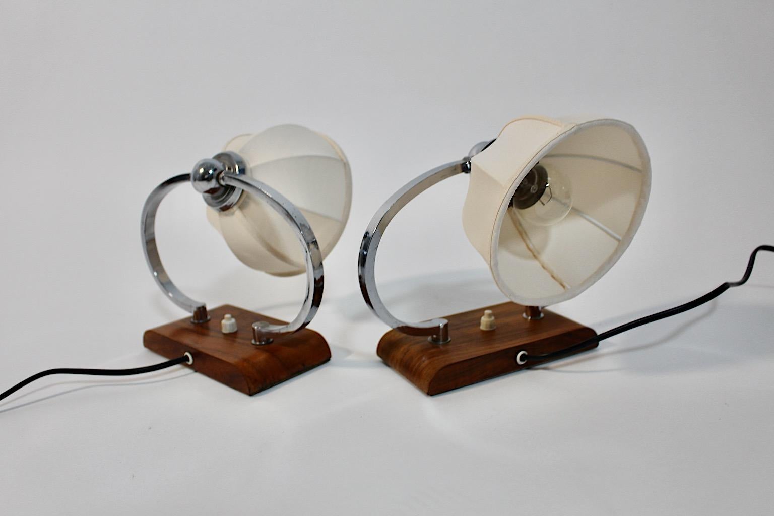 Art Deco vintage pair of bedside lamps or table lamps from walnut and chromed metal circa 1925 Austria.
A stunning pair of bedside lamps or table lamps with curved mounting from chromed metal and rectangular base from walnut each with one E 27