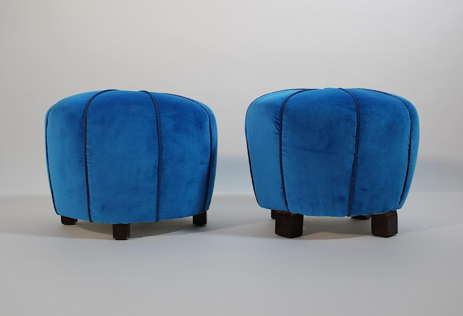 Art Deco vintage pair of poufs or stools circular shaped with 
stained beech feet 1930s Austria.
An amazing pair of poufs or stools newly upholstered and covered with wonderful deep blue velvet fabric and blue cords in original shape.
A round button