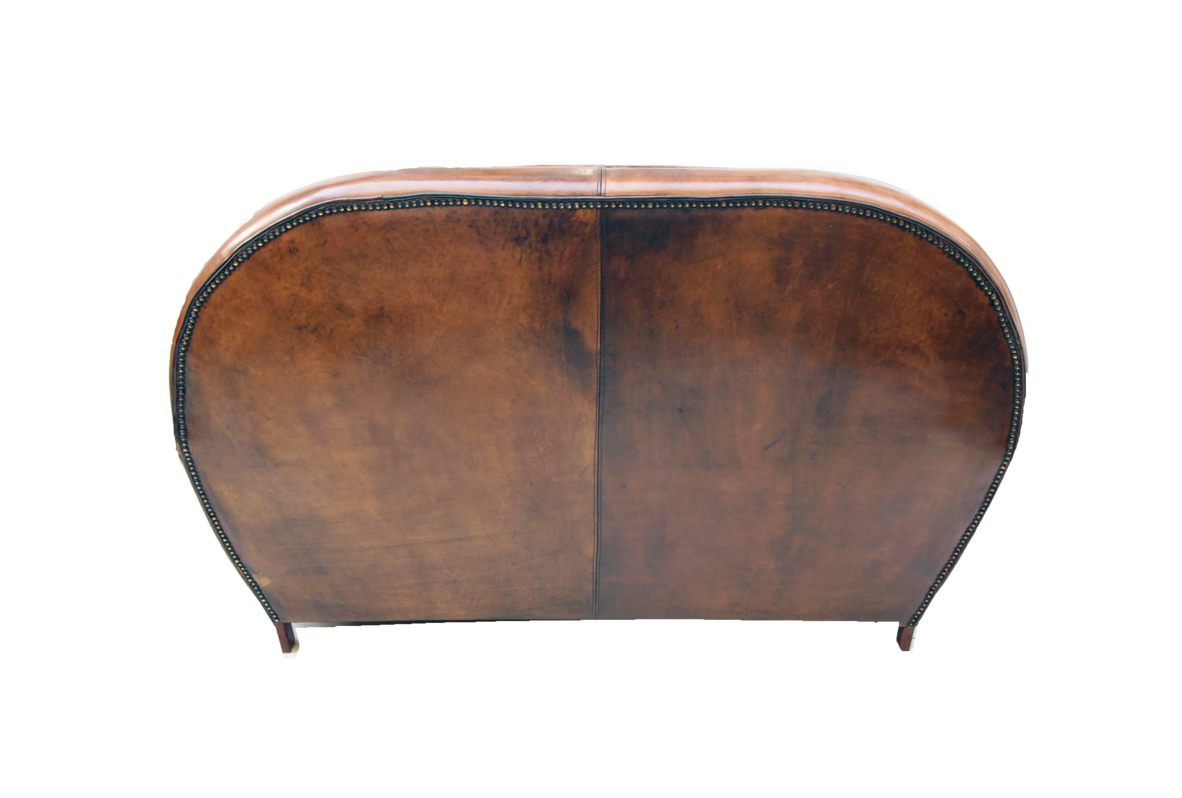 Ce canapé club, est recouvert de cuir de mouton patiné à la main. Le canapé a une très belle forme Art Déco. Le cuir est très solide et l'assise est très confortable. 

 