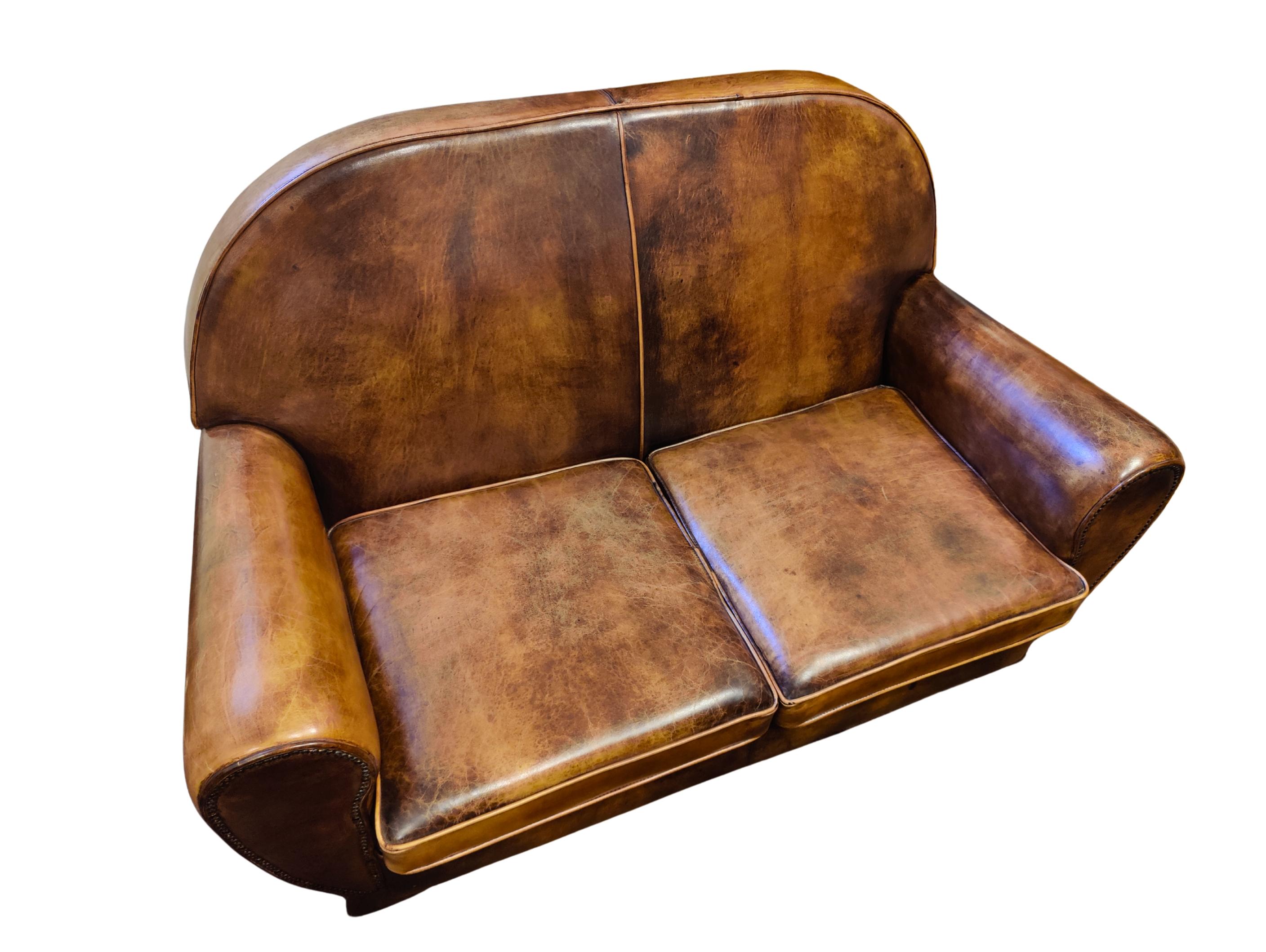 Ce canapé club, est recouvert de cuir de mouton patiné à la main. Le canapé a une très belle forme Art Déco. Le cuir est très solide et l'assise est très confortable. 

 