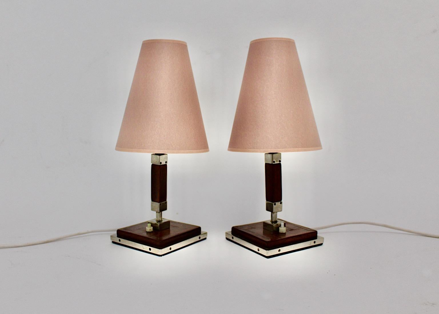 Art Deco vintage pair of table lamps or night stands from brown stained and lacquered oakwood with elegant chromed metal details at the edges and new lampshades from paper in soft mauve color tone.
The elegant styling from the table lamps is