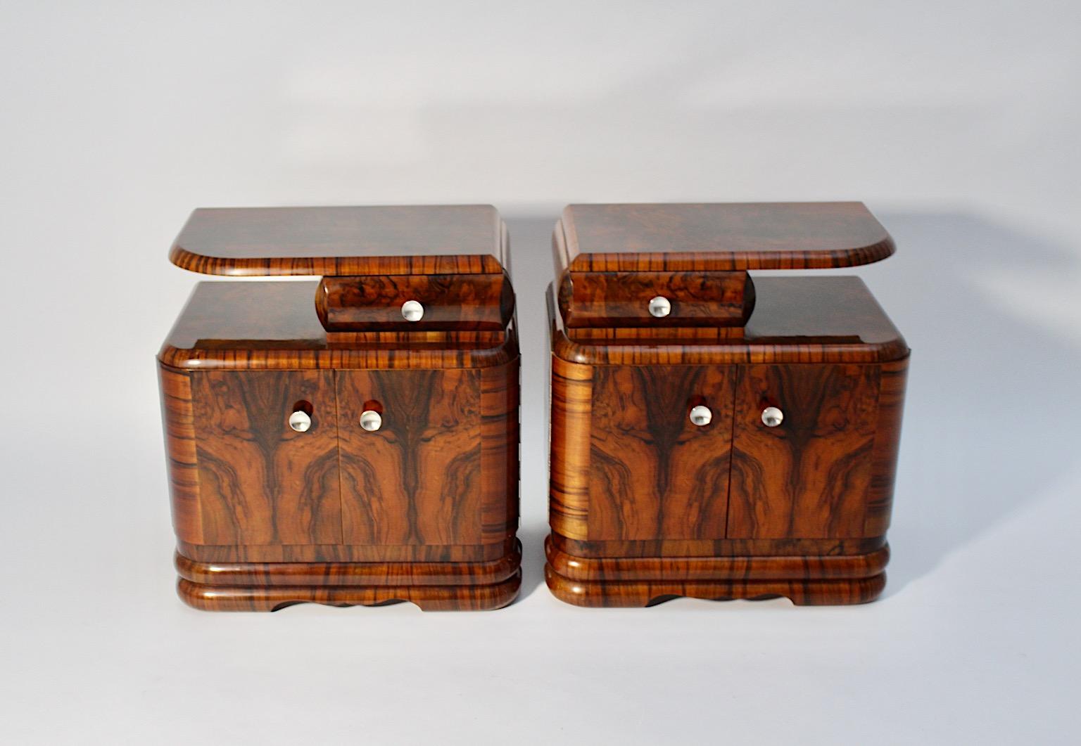 Art Deco vintage pair duo nightstands from walnut and nickel, 1930s Vienna.
An elegant pair duo of nightstands from lively walnut veneer in warm chocolate brown color in a stunning curved shape.
These nightstands feature at the upper part one drawer