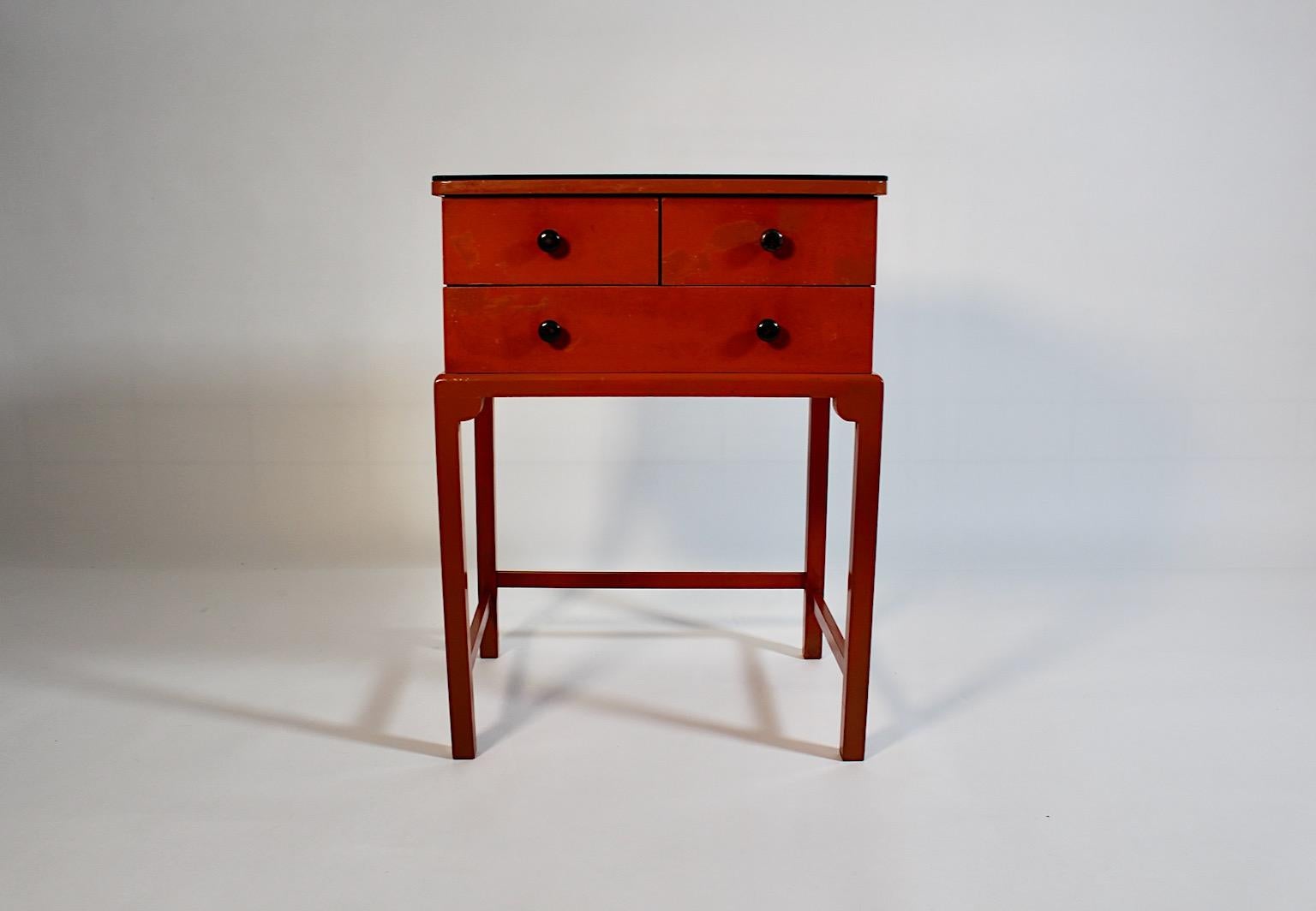 Cassapanca o tavolino vintage in legno di abete rosso laccato in arancione bruciato con maniglie a bottone in legno nero e sormontato da un piatto originale in vetro nero, anni '30.
Un sofisticato  piccola cassapanca in abete rosso con quattro ( 4 )