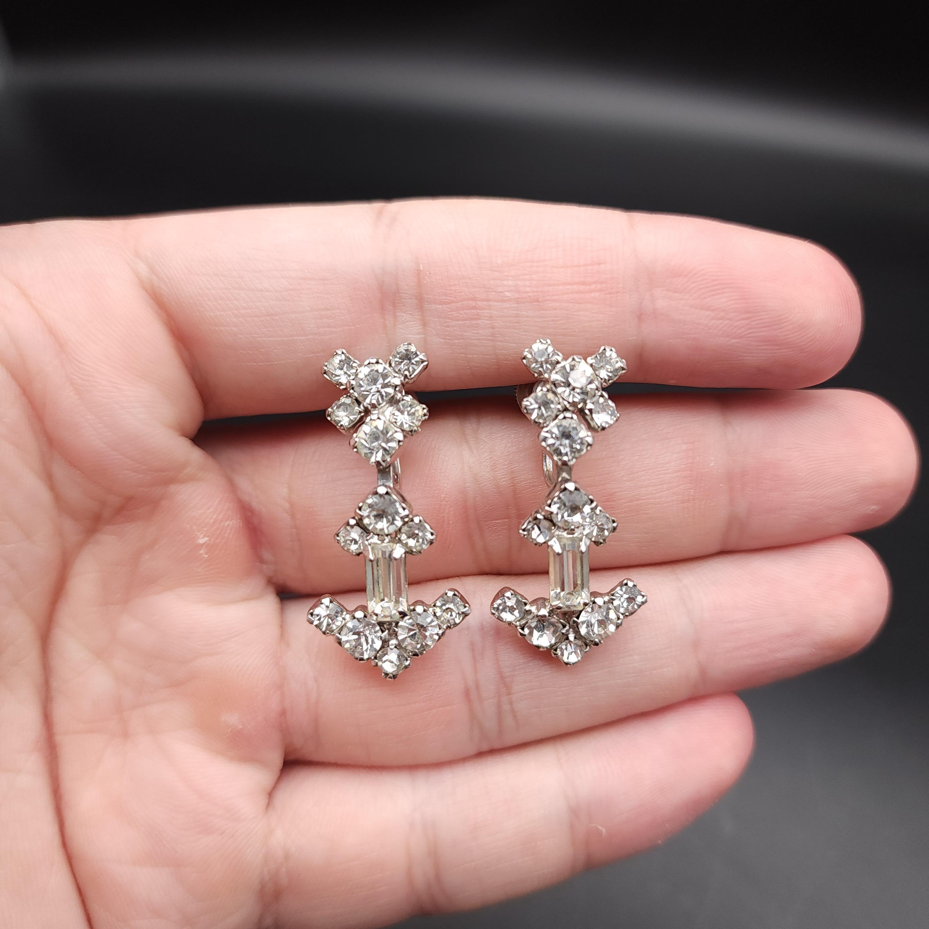 Each earrings: 1 3/8 in. length by 5/8 inch width at widest part

Step back in time with these retro art deco clear crystal earrings, a pair that exudes vintage charm and elegance. These exquisite earrings feature prong-set round and baguette