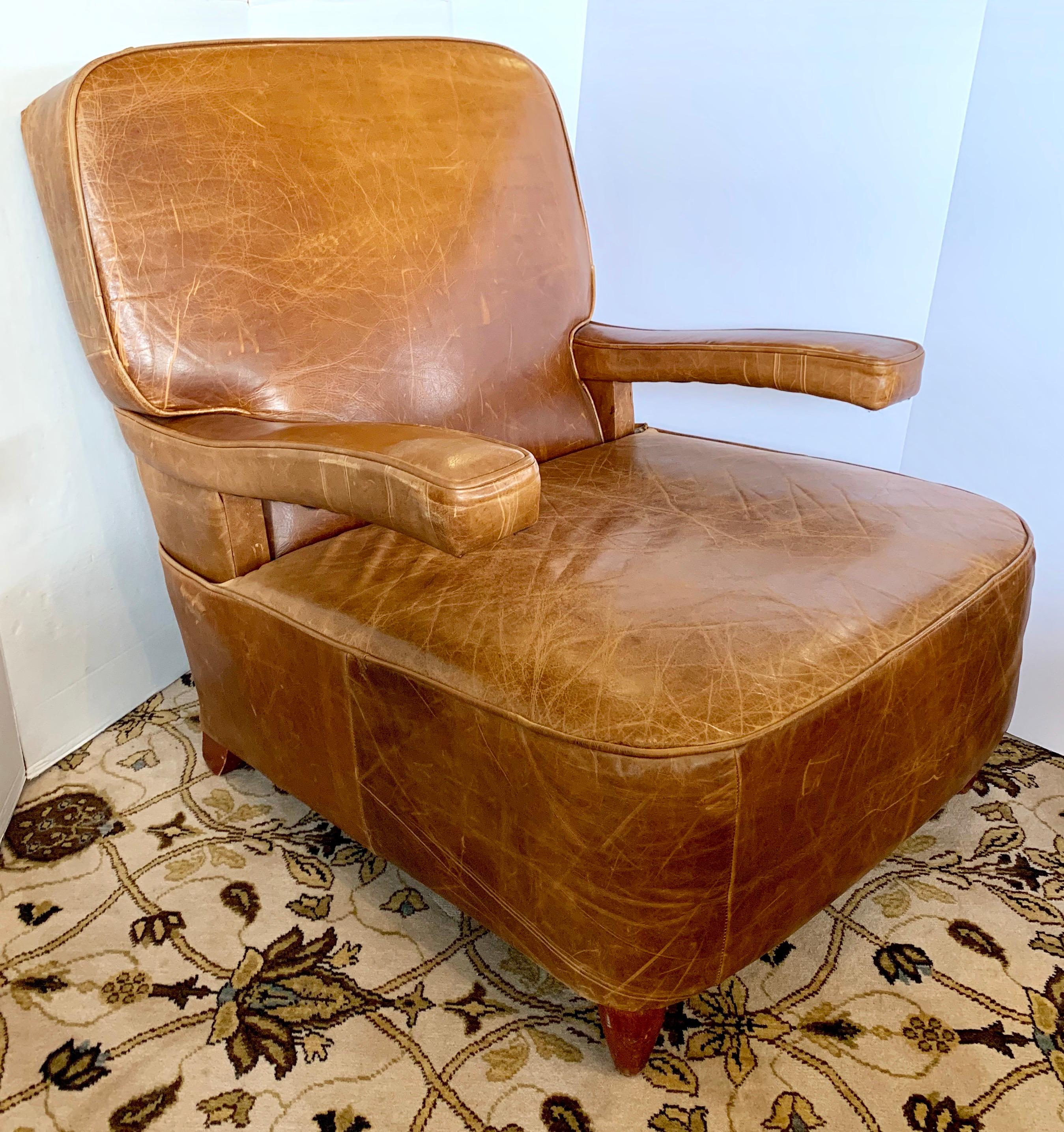 Elegant vintage French leather club chair has floating arms. The leather is brown and of the highest quality with a beautiful patina only acquired through age and use.