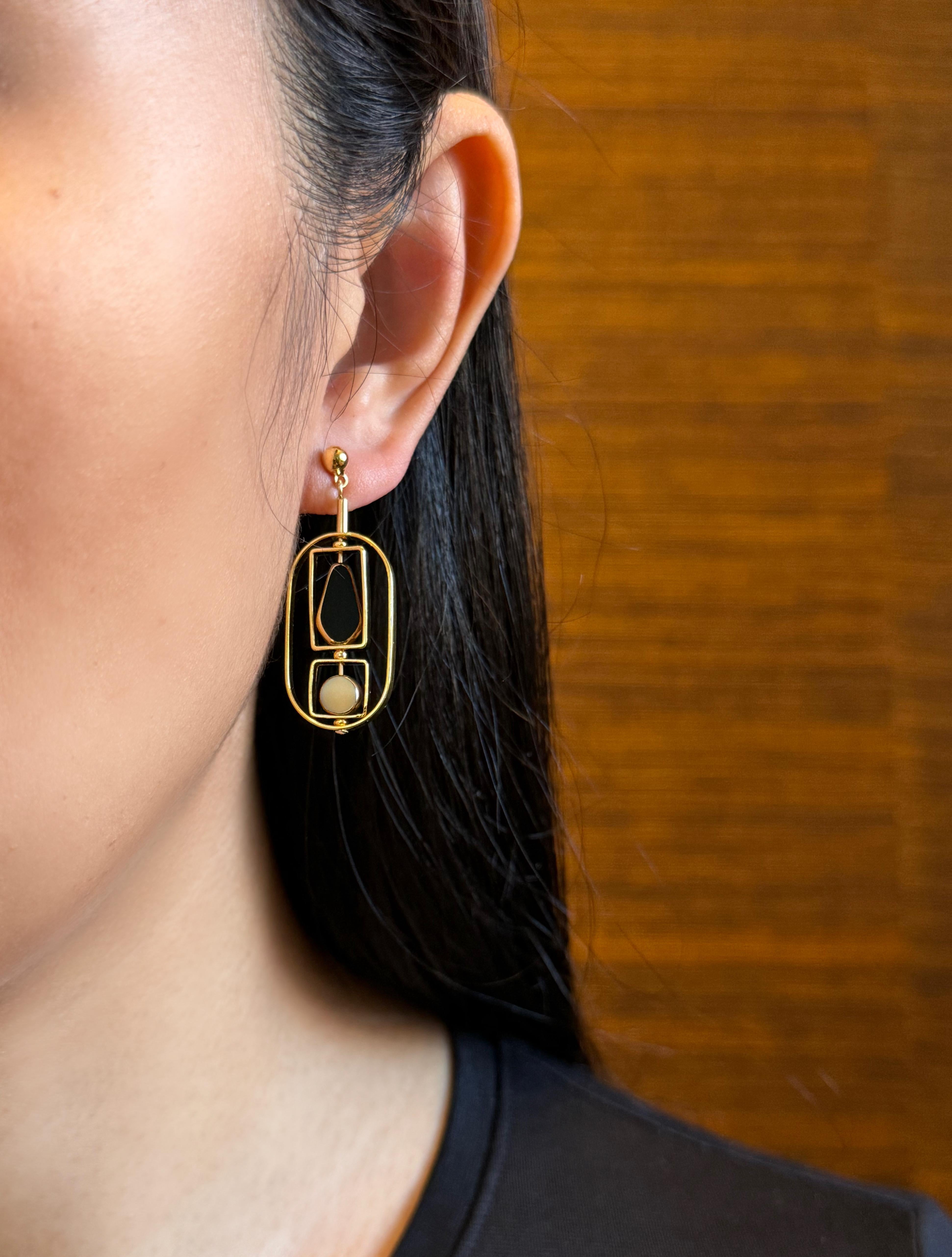 The earrings are lightweight and are made to rotate and reposition with movement. The earrings consist of small black kite and small beige circle-shaped beads. They are new old stock vintage German glass beads that are framed with 24K gold. The