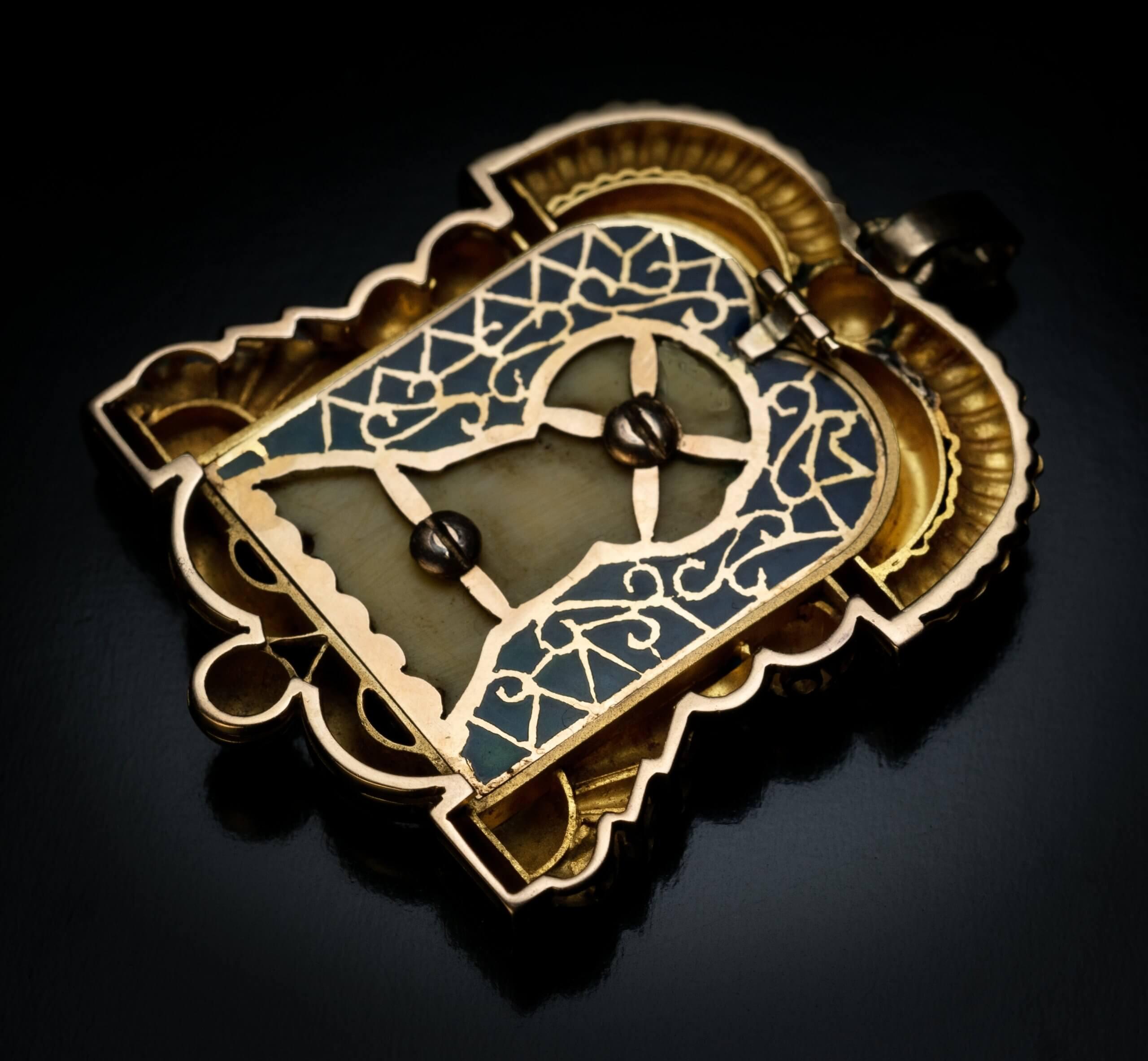 Spanien, um 1930

Dieser verschnörkelte Anhänger aus 18 Karat Gold und Platin aus der Zeit des Art déco zeigt eine aus Knochen geschnitzte Büste der betenden Madonna, die mit lila, brauner und goldener Farbe schattiert ist. Die Schnitzerei ist im