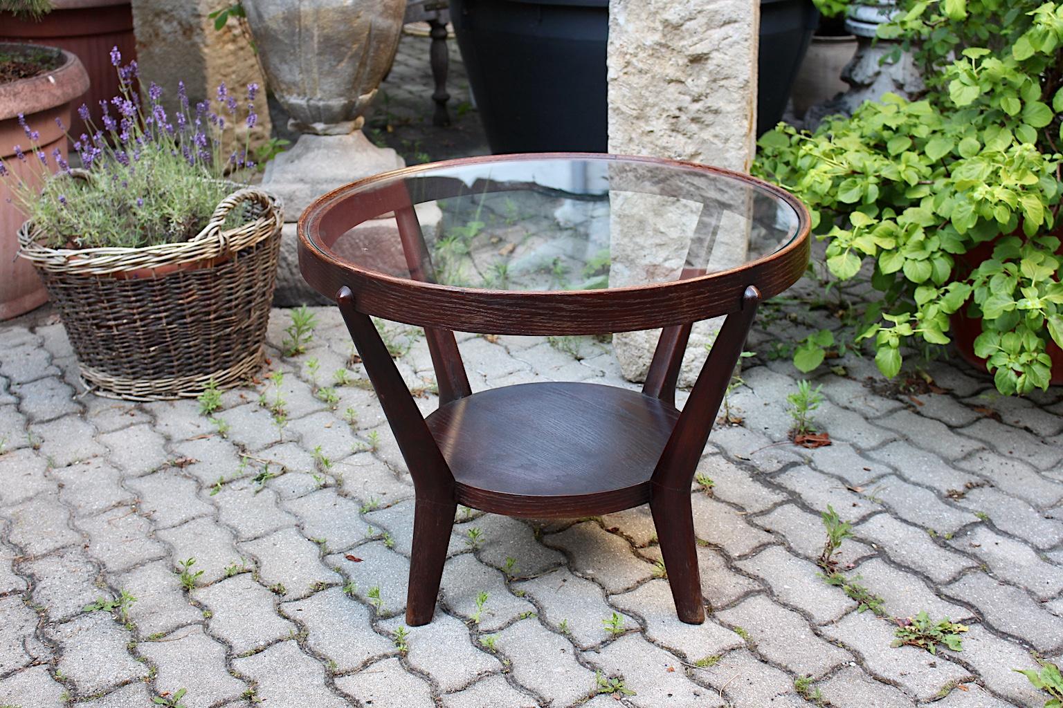 An Art Deco vintage oakwood coffee table, which was designed by K. Kozelka and A. Kropacek for Ceske Umelecke Dilny, Czech Republic 1940s.
The round formed stained oakwood coffee table has a clear glass top. Four slightly curved rounded legs hold a