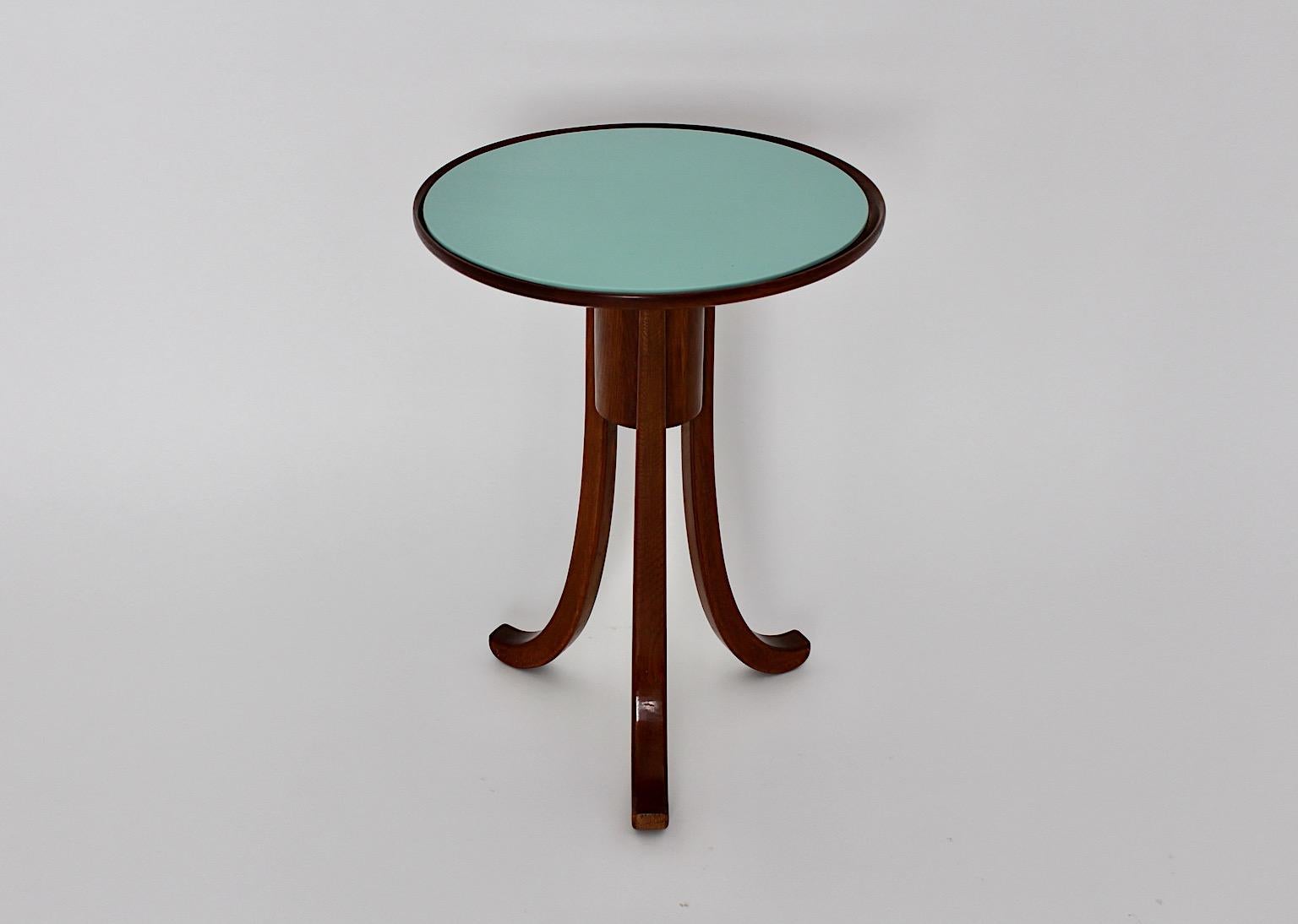 Art Deco vintage side table attributed to Josef Frank for Haus & Garten 1930s Vienna from brown stained oak and green teal glass plate in round shape with three legs.
While the base was made from solid oak the top was made from oak veneer with a