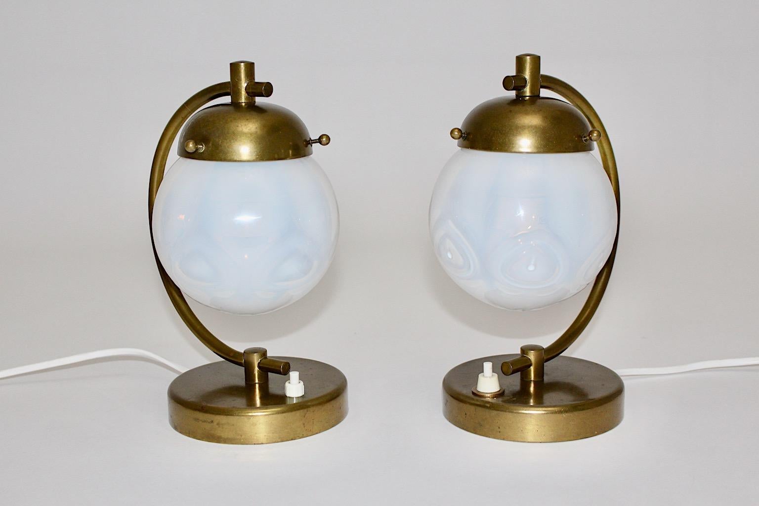 Art Deco vintage pair of table lamps or bedside lamps or sconces from brass with dome glass shades from blue opaline milky glass designed and executed in Austria 1930s.
While the amazing blue opaline glass shades dome like are fitted with three ball