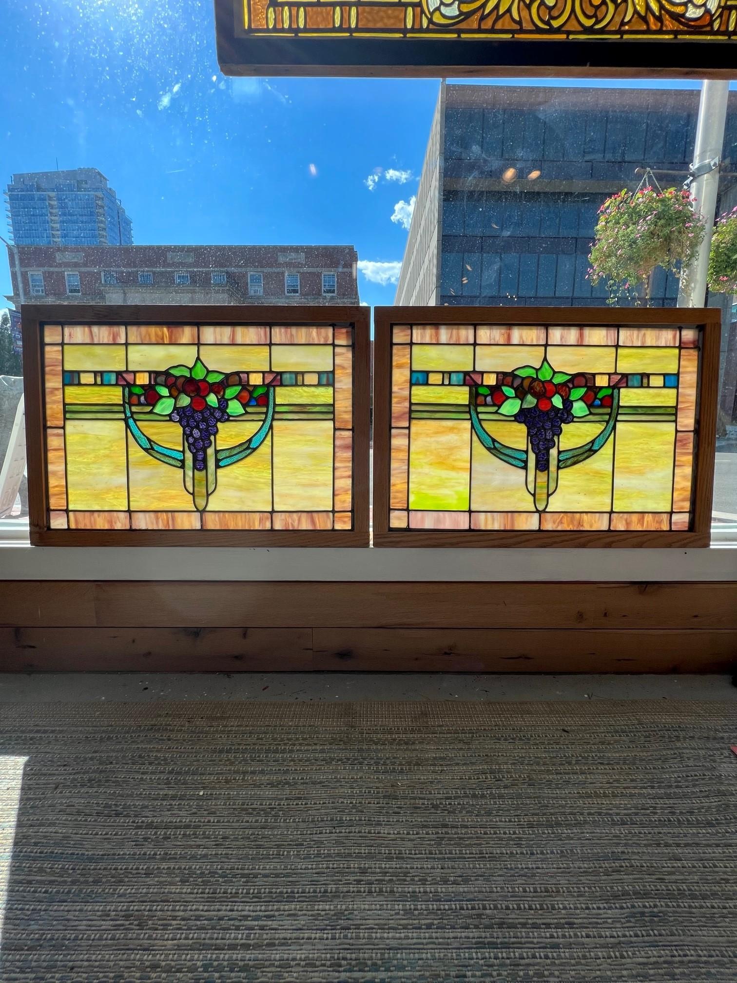 Beautiful pair of Art Deco stained glass windows with hanging grapes in the center. The colors are amazing in this pair of windows perfect for a kitchen or wine ceiler. In great condition no breaks in the glass and a new oak frame very sturdy.